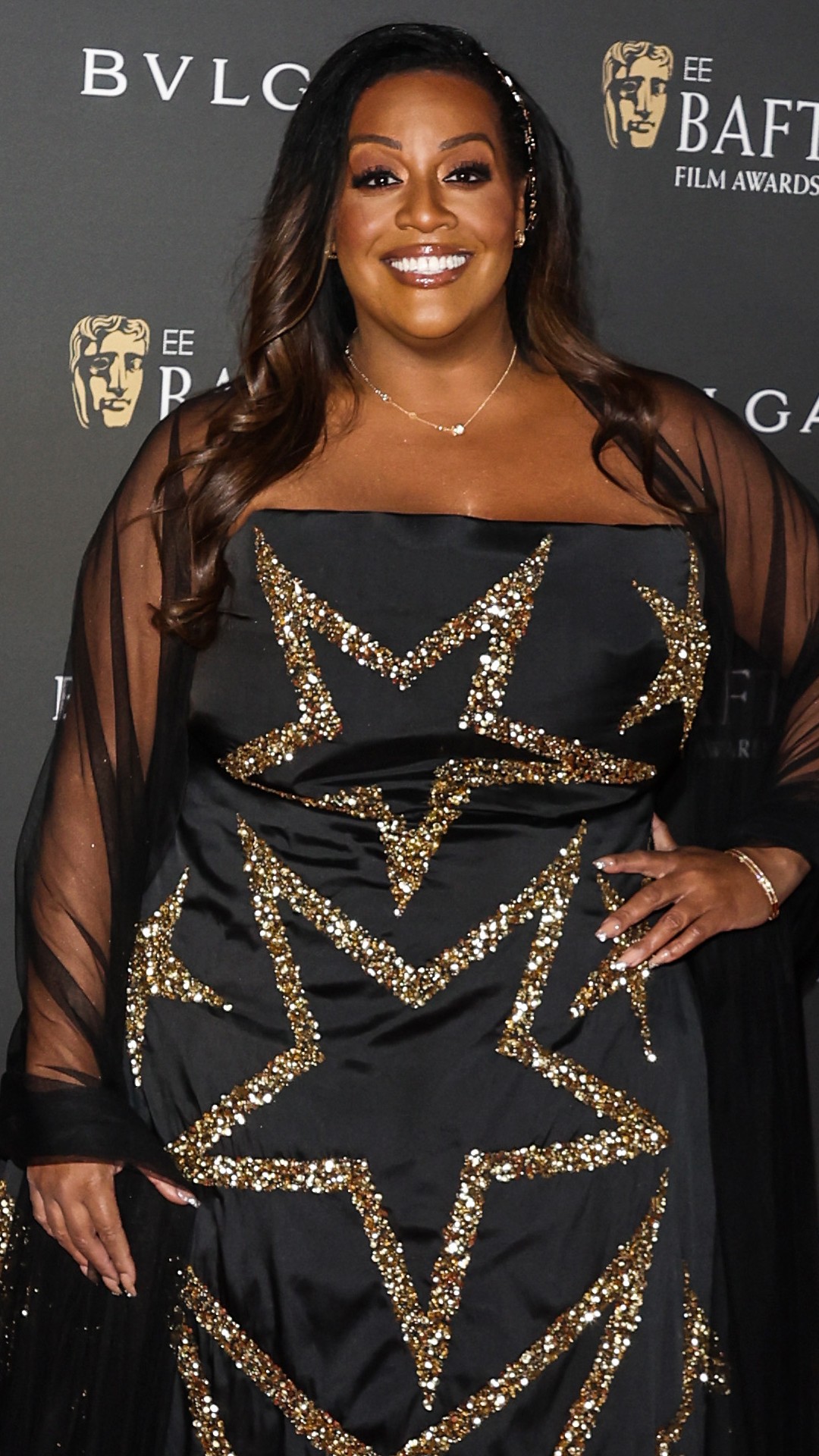 Alison Hammond wearing a black gown with gold stars on the red carpet