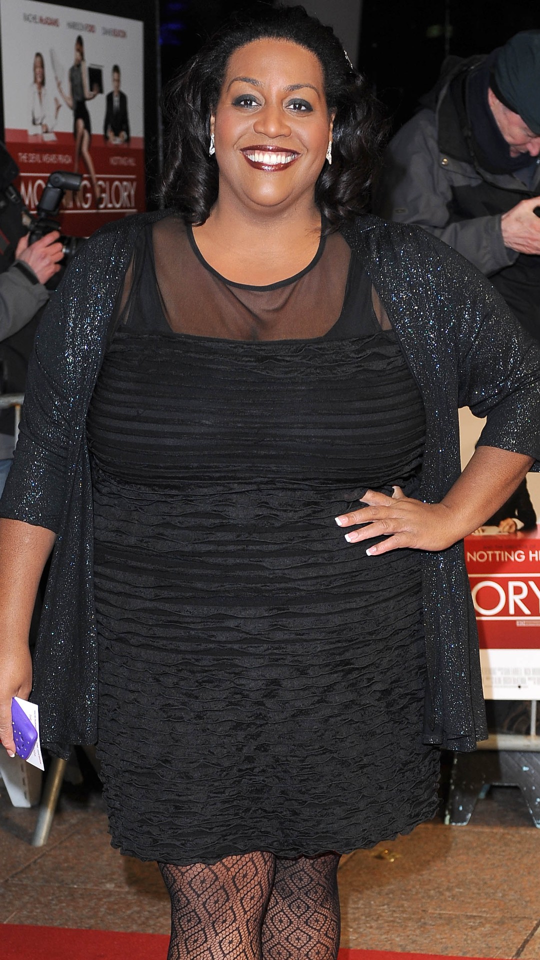Alison Hammond wearing a little black dress with one hand on her hip whilst smiling on the red carpet