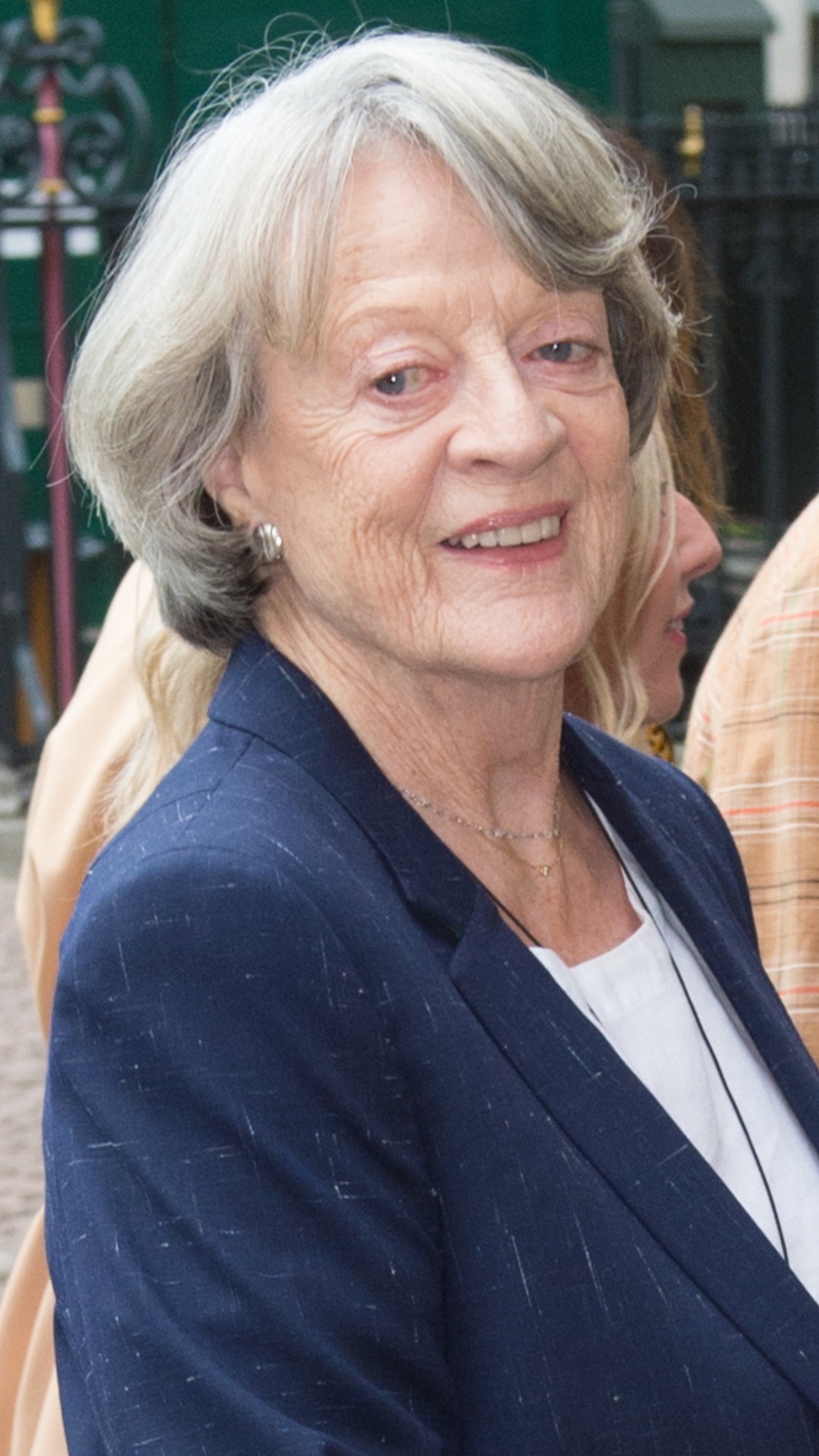 Dame Maggie Smith smiling wearing a navy blazer