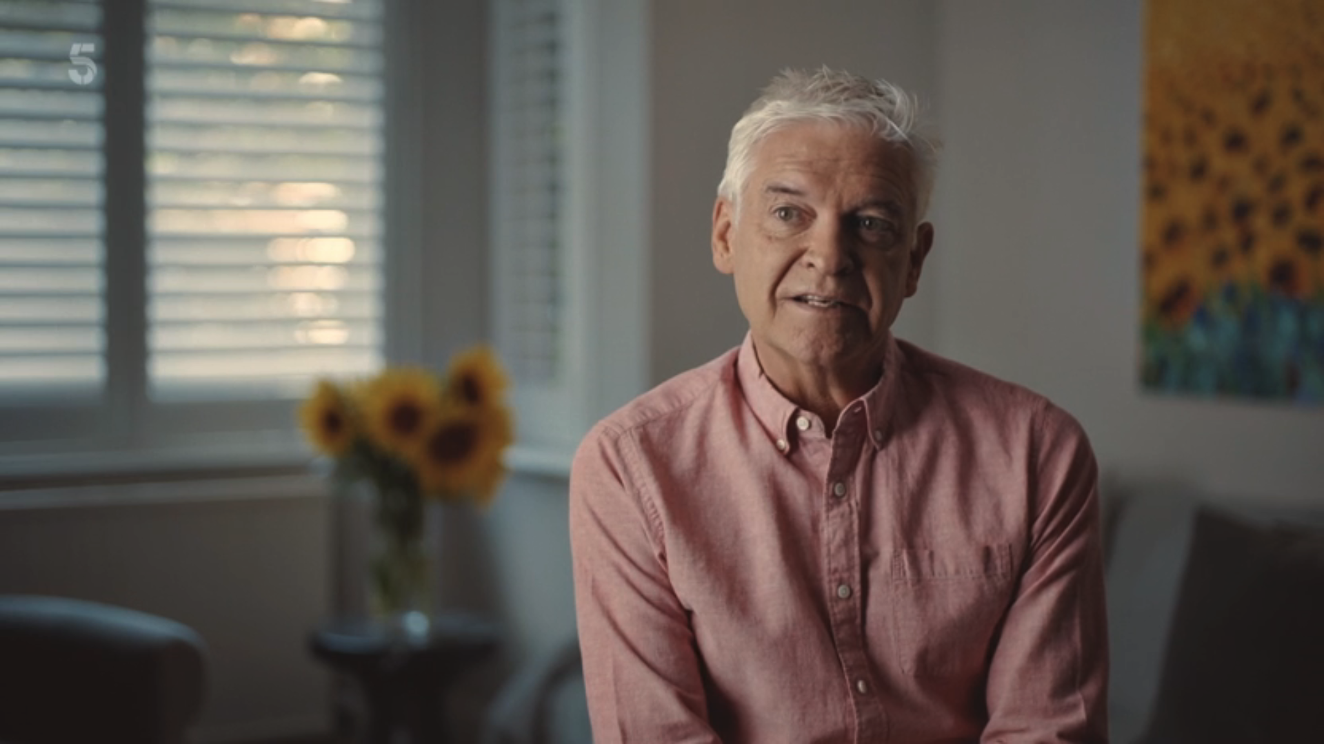 Phillip Schofield sitting in a living room in a pink shirt