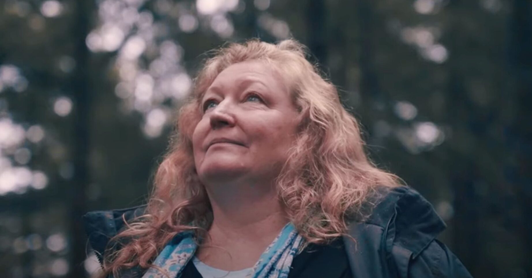 Charlie Dimmock looks up at the sky in a forest
