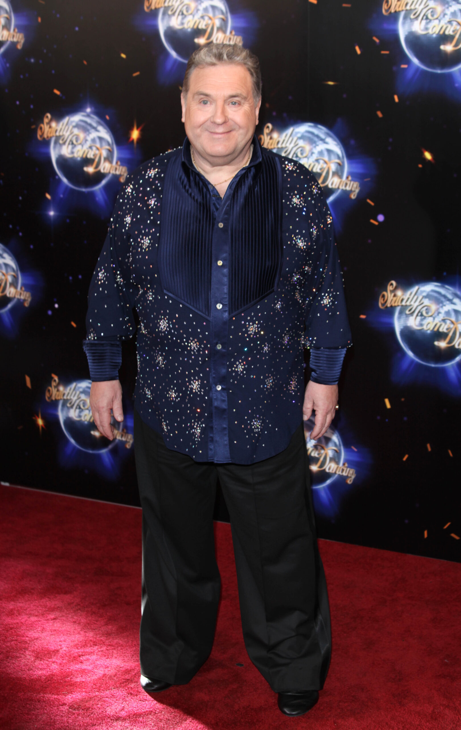 Russell Grant smiling against the Strictly backboard