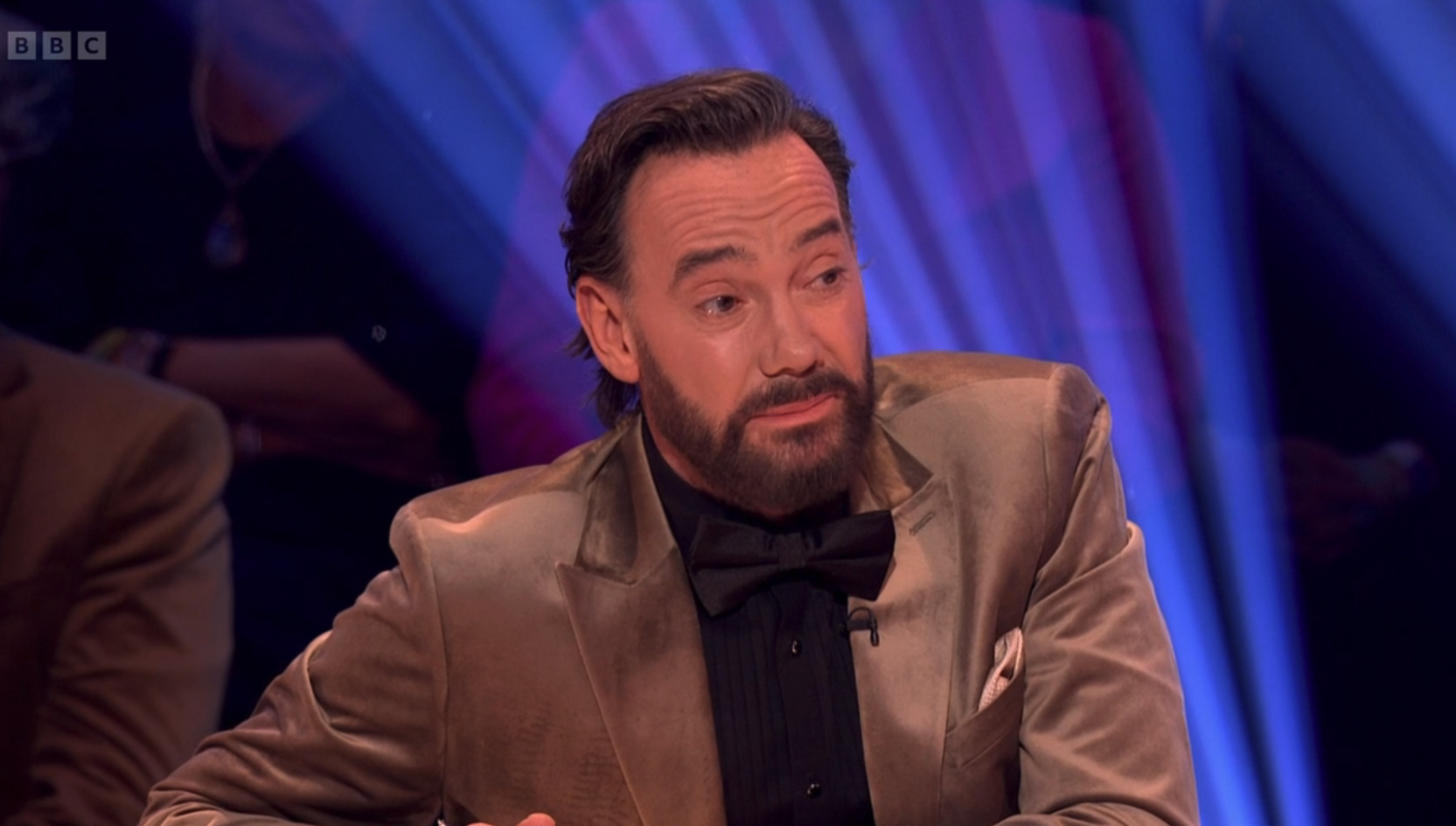 Craig Revel Horwood speaking on Strictly in a brown jacket