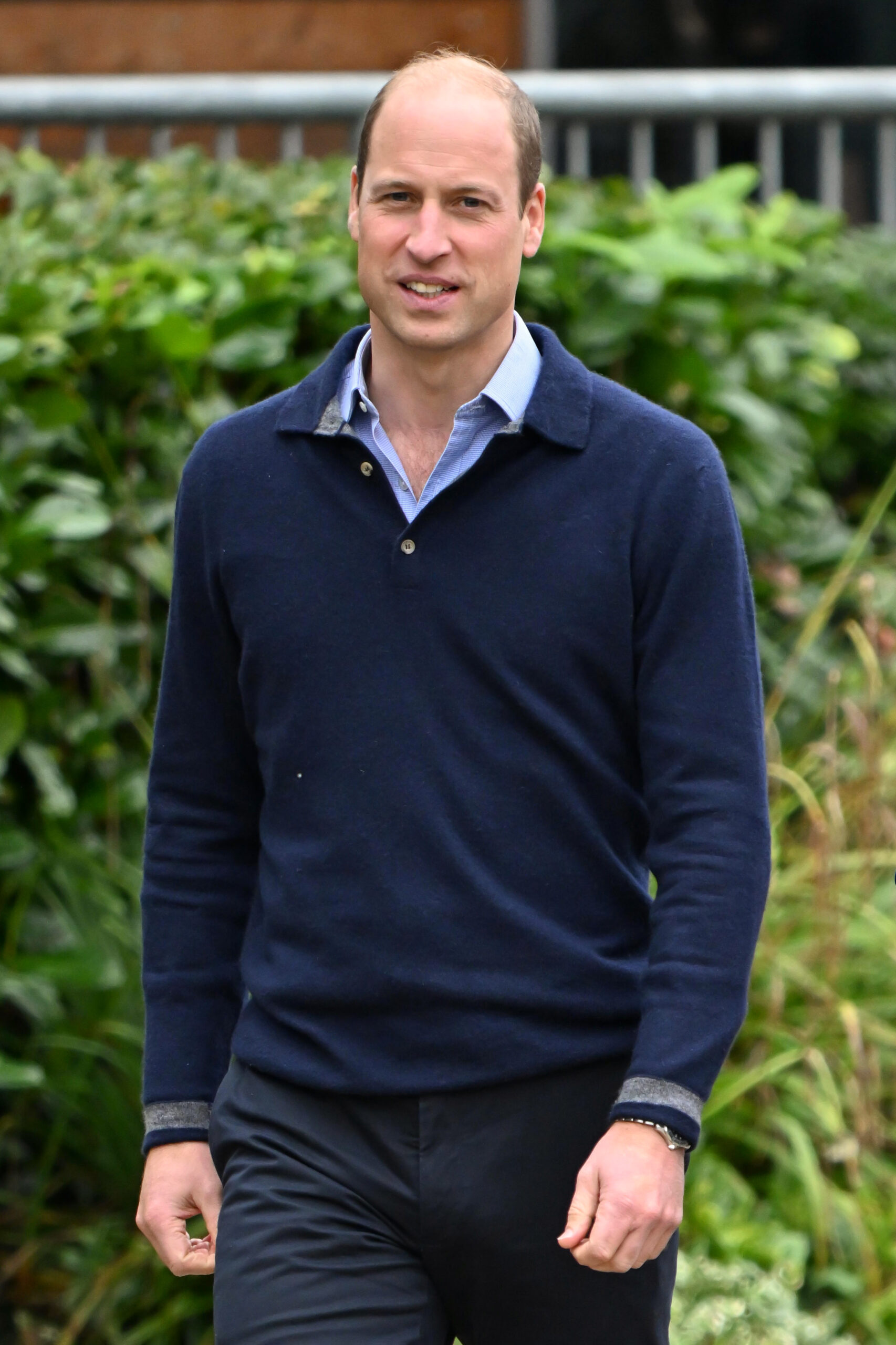 Prince William smiling in a navy jumper and blue shirt