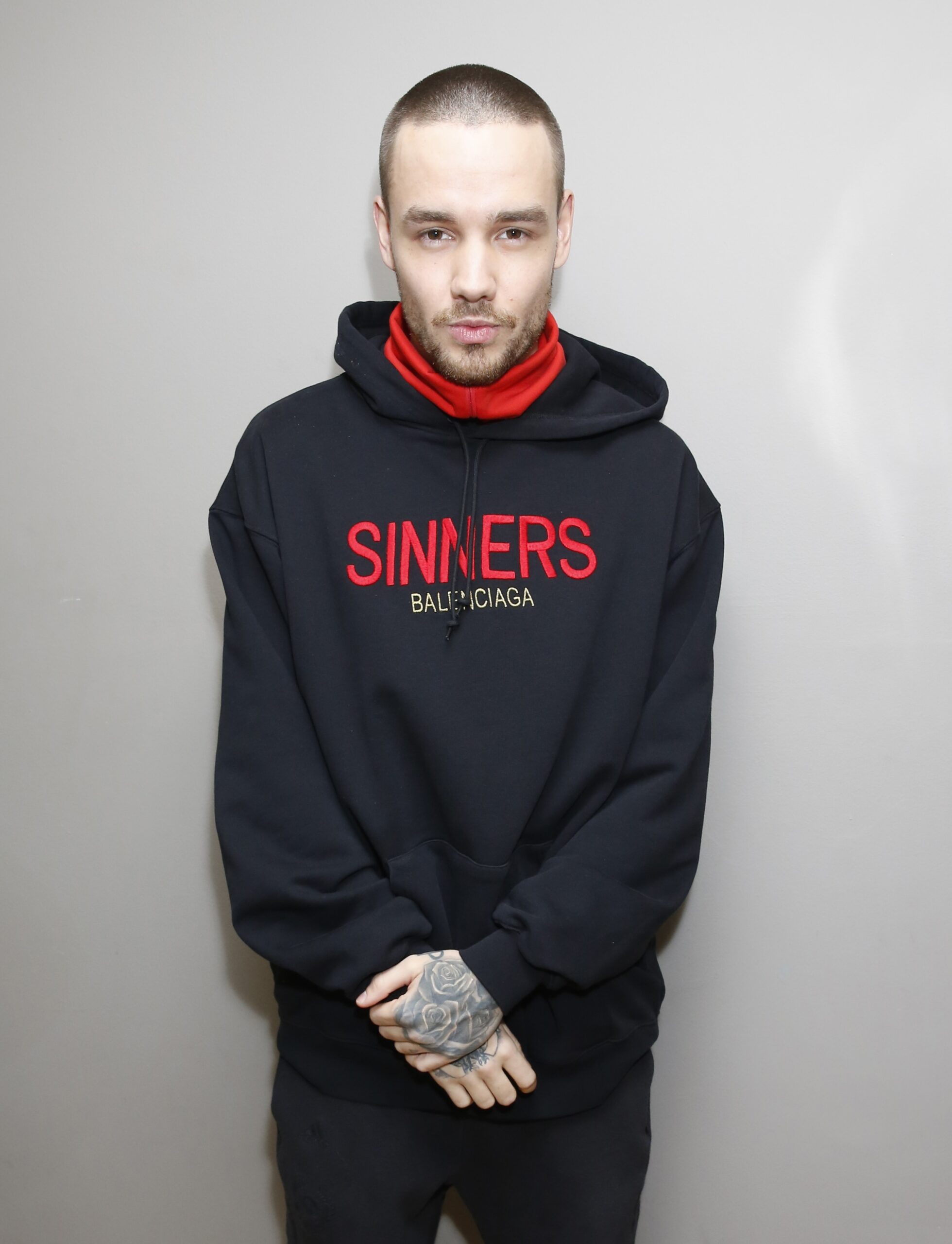 Liam Payne wearing a black hoodie with red writing on