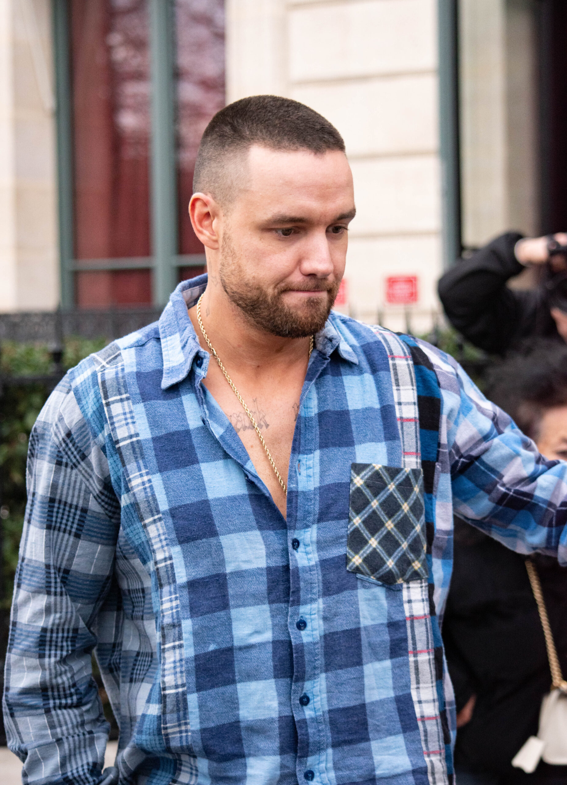 Liam Payne looking sad wearing a blue checked shirt