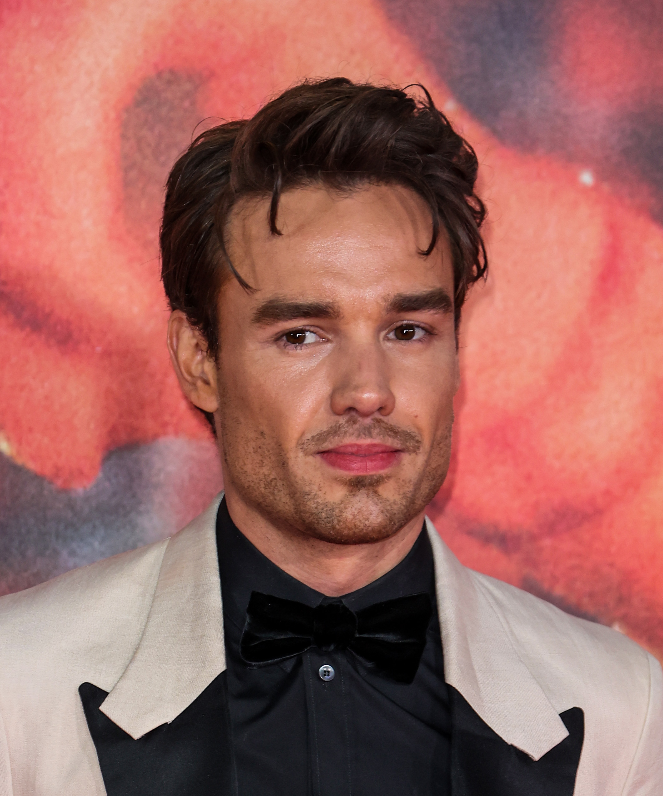 Liam Payne in a cream jacket with a straight face