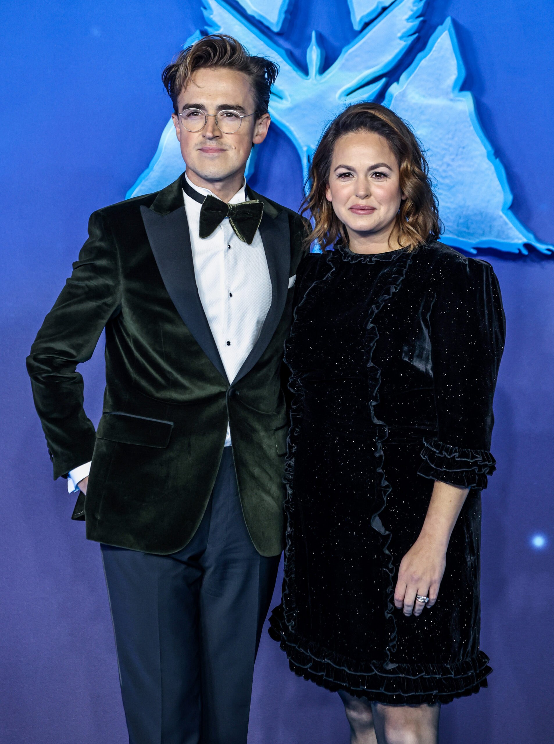 Giovanna and Tom Fletcher standing against a blue background