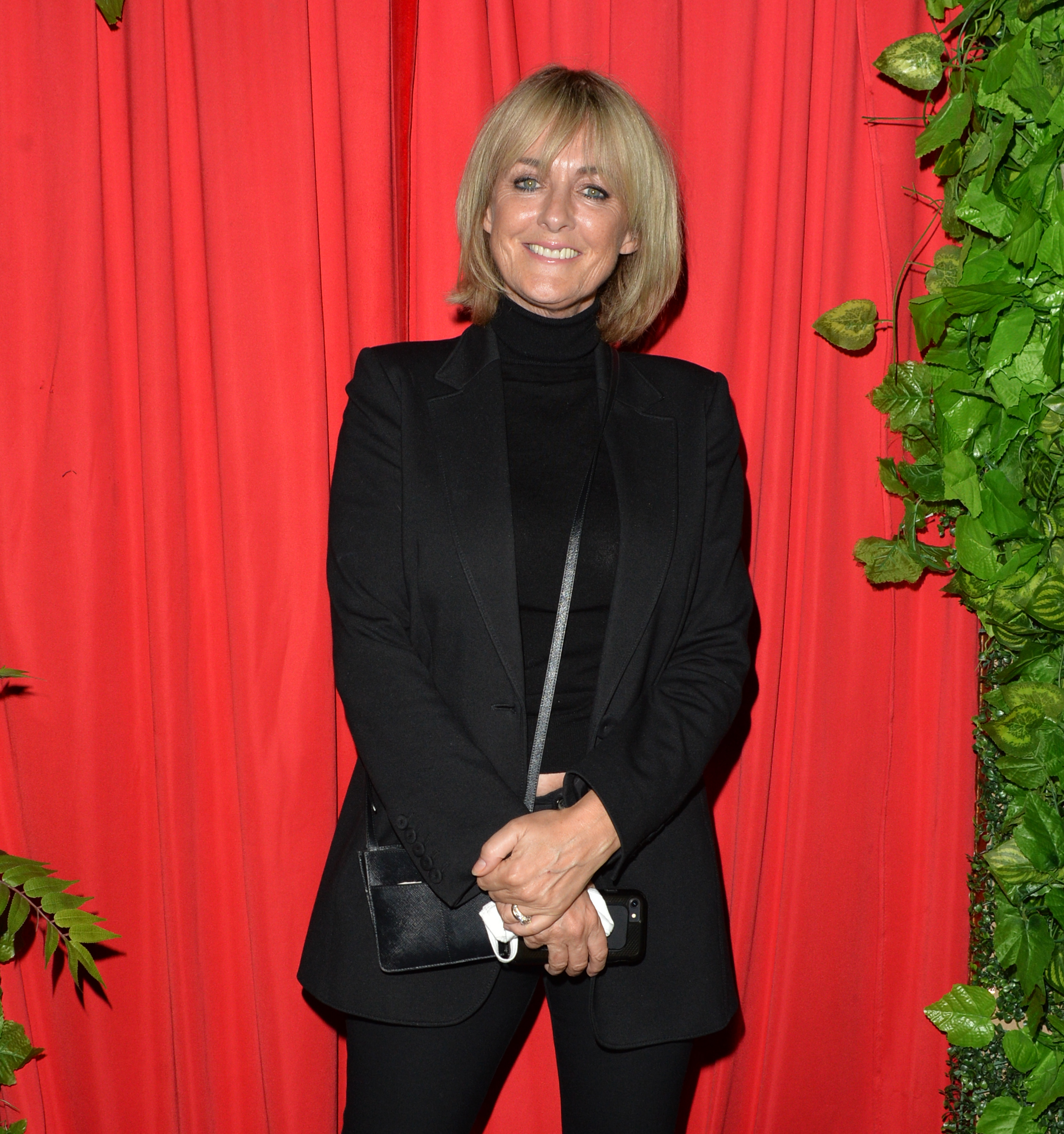 Jane Moore smiling against a rd backdrop