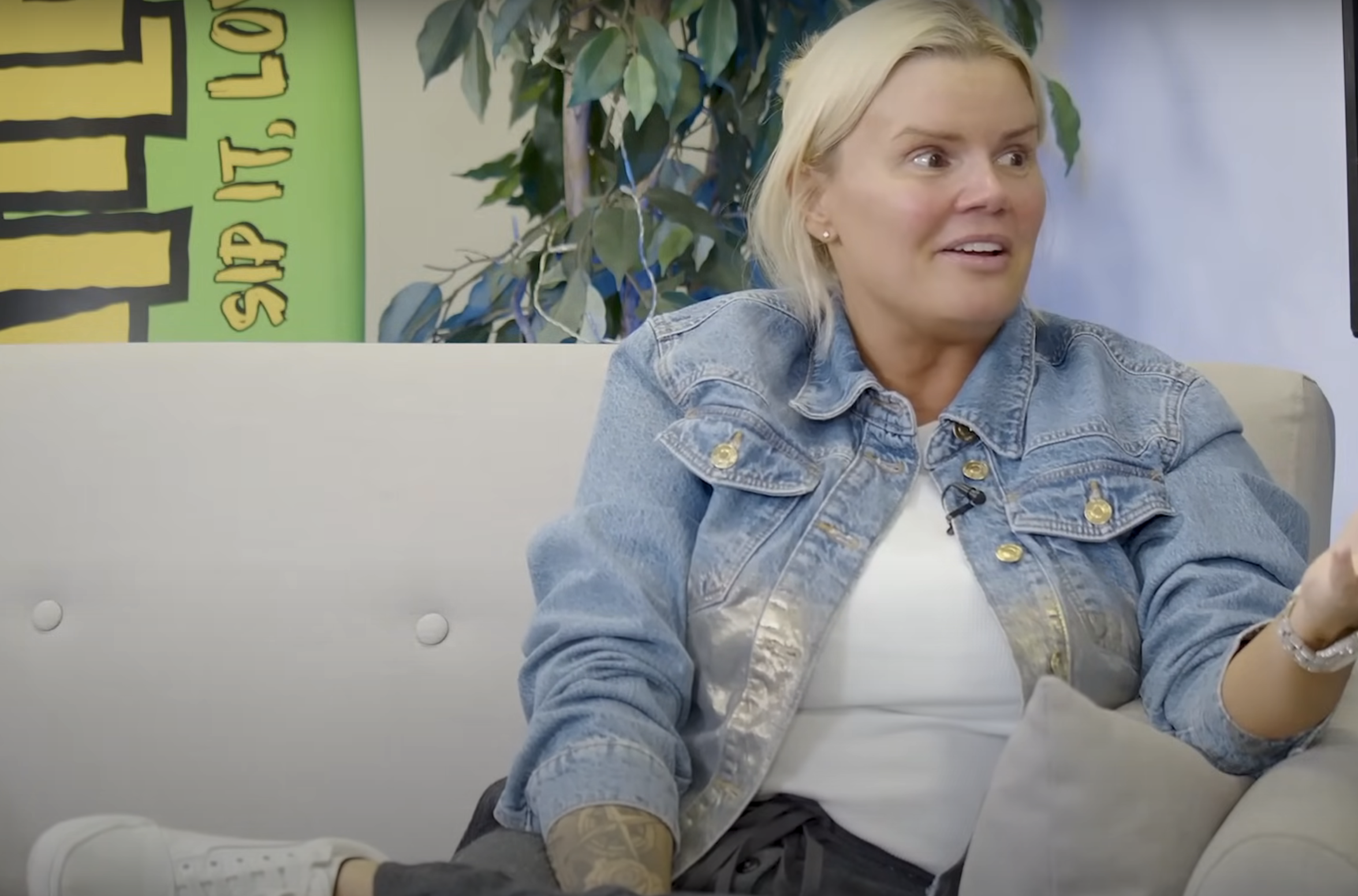 Kerry Katona in a denim jacket sitting on a cream-coloured sofa while being interviewed