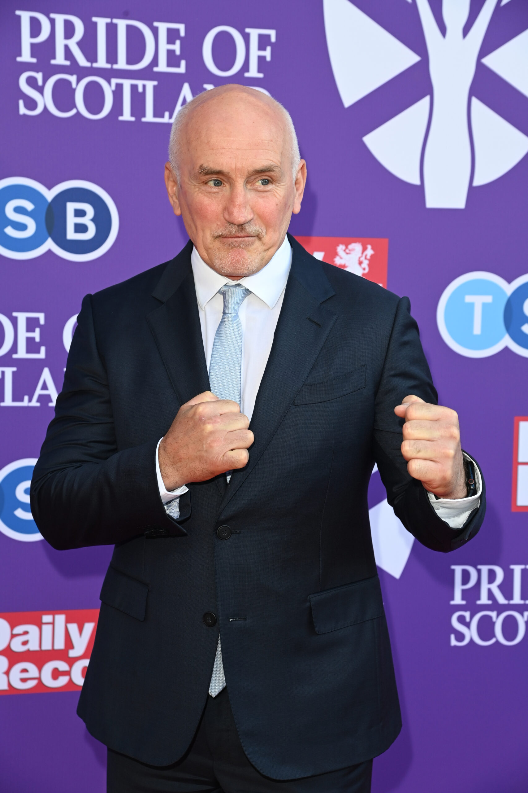 Barry McGuigan posing with his fists up in a suit