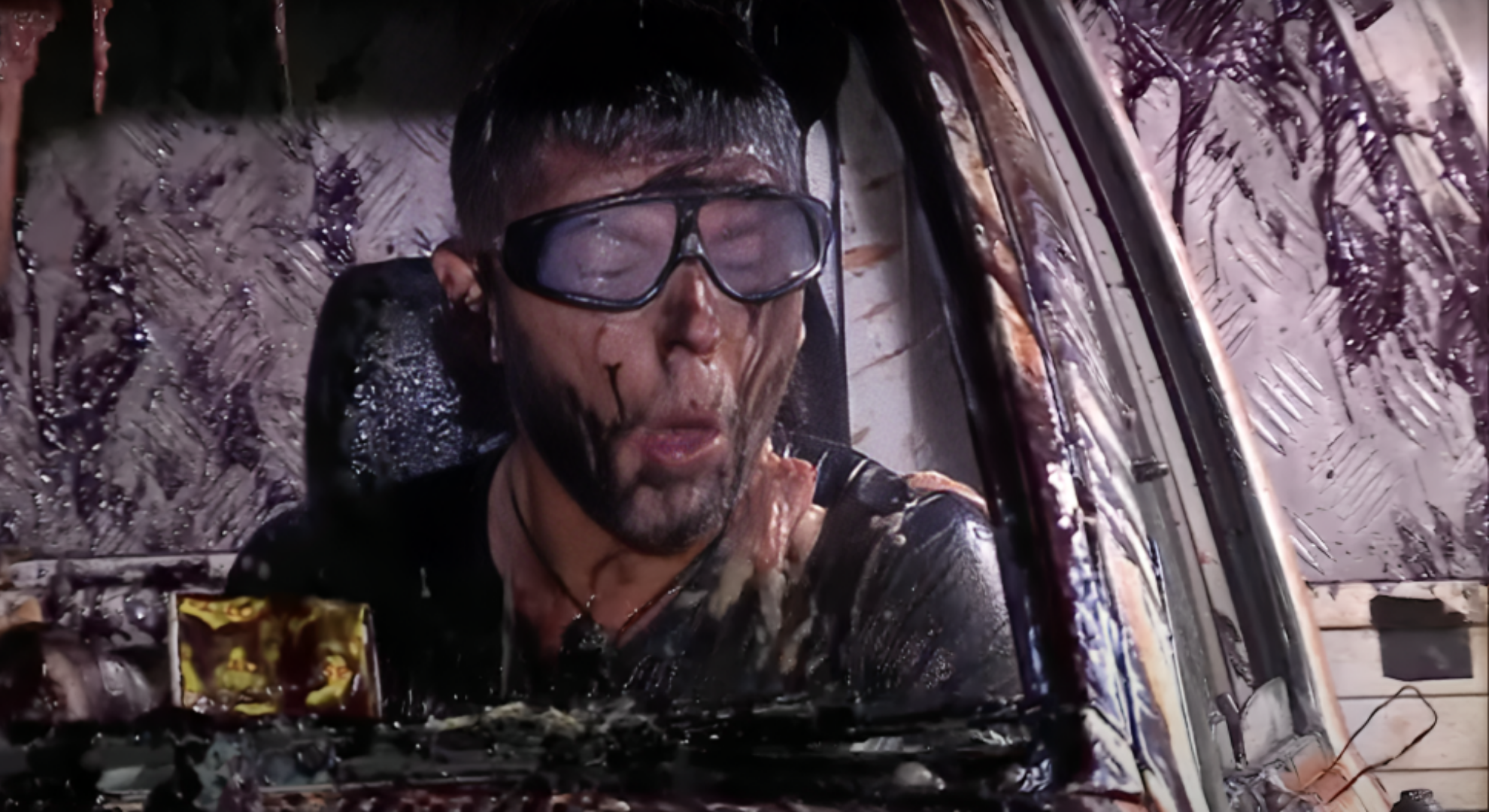 Dean McCullough is covered in slime wearing safety goggle in the front seat of a car during Bushtucker trial on I'm A Celebrity