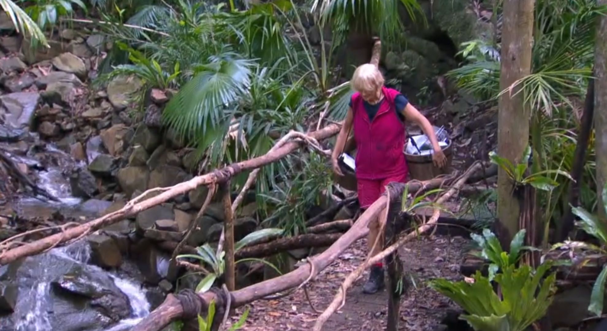 Jane Moore carrying dirty dishes in camp on I'm A Celebrity
