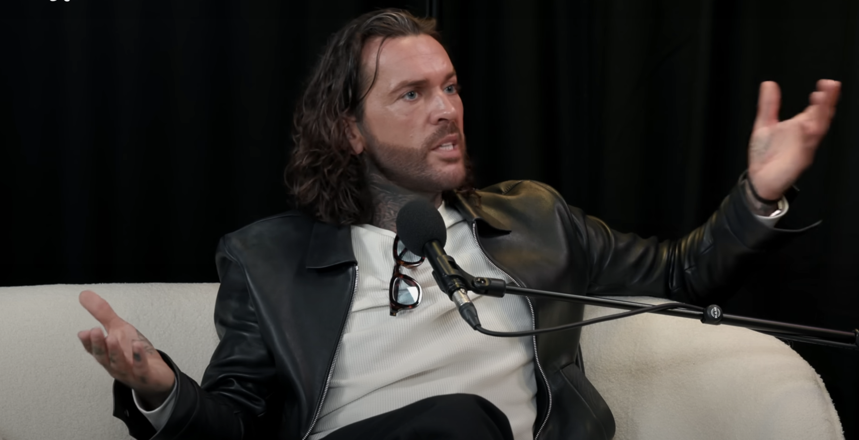 Pete Wicks in a leather jacket on the sofa with a studio microphone