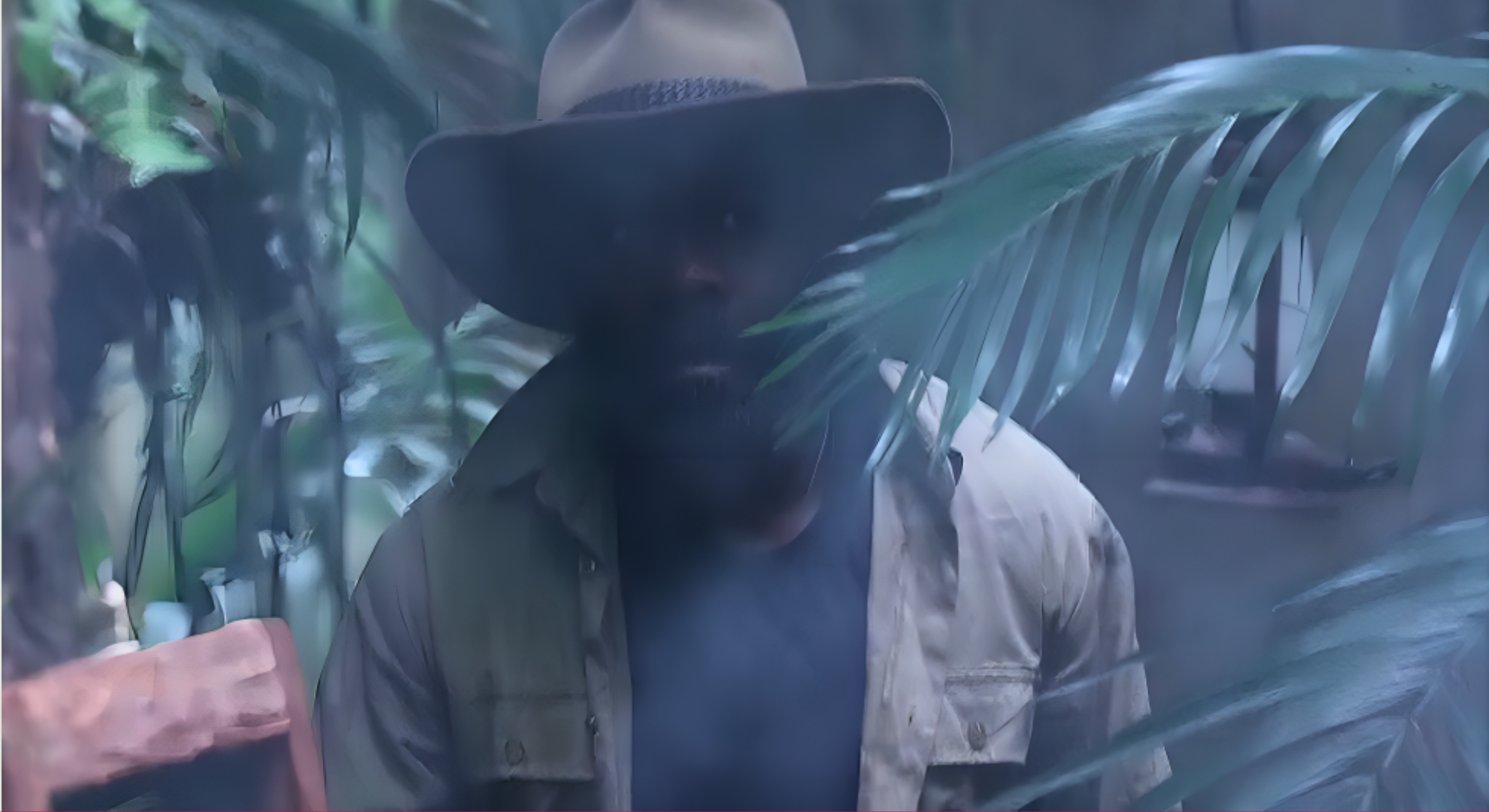 Melvin is walking through the misty I'm A Celebrity jungle on the way to fetch water. He looks tired.