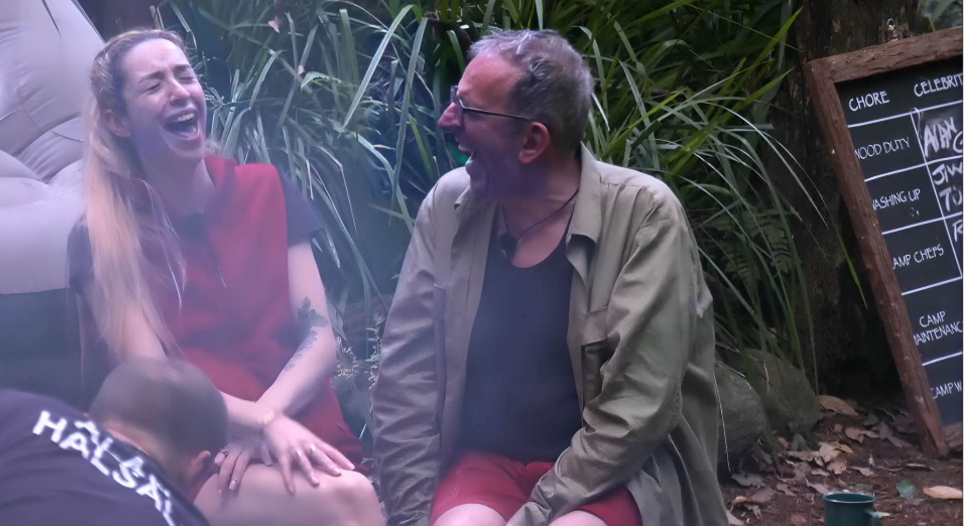 On the left is GK Barry wearing the I'm A Celebrity standard clothes, she is laughing with Reverend Richard Coles who sits next to her.