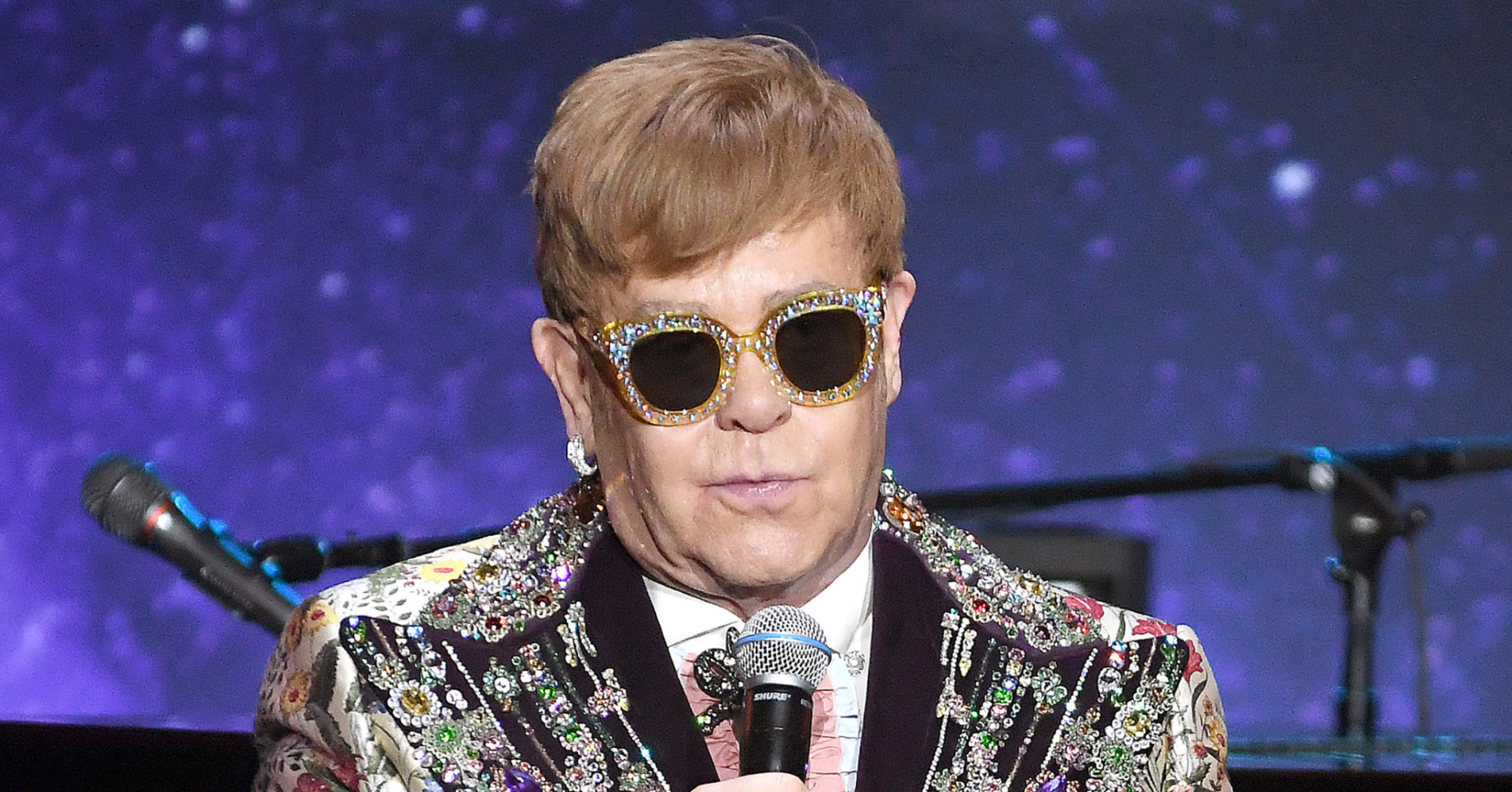 Elton John on stage holding a microphone
