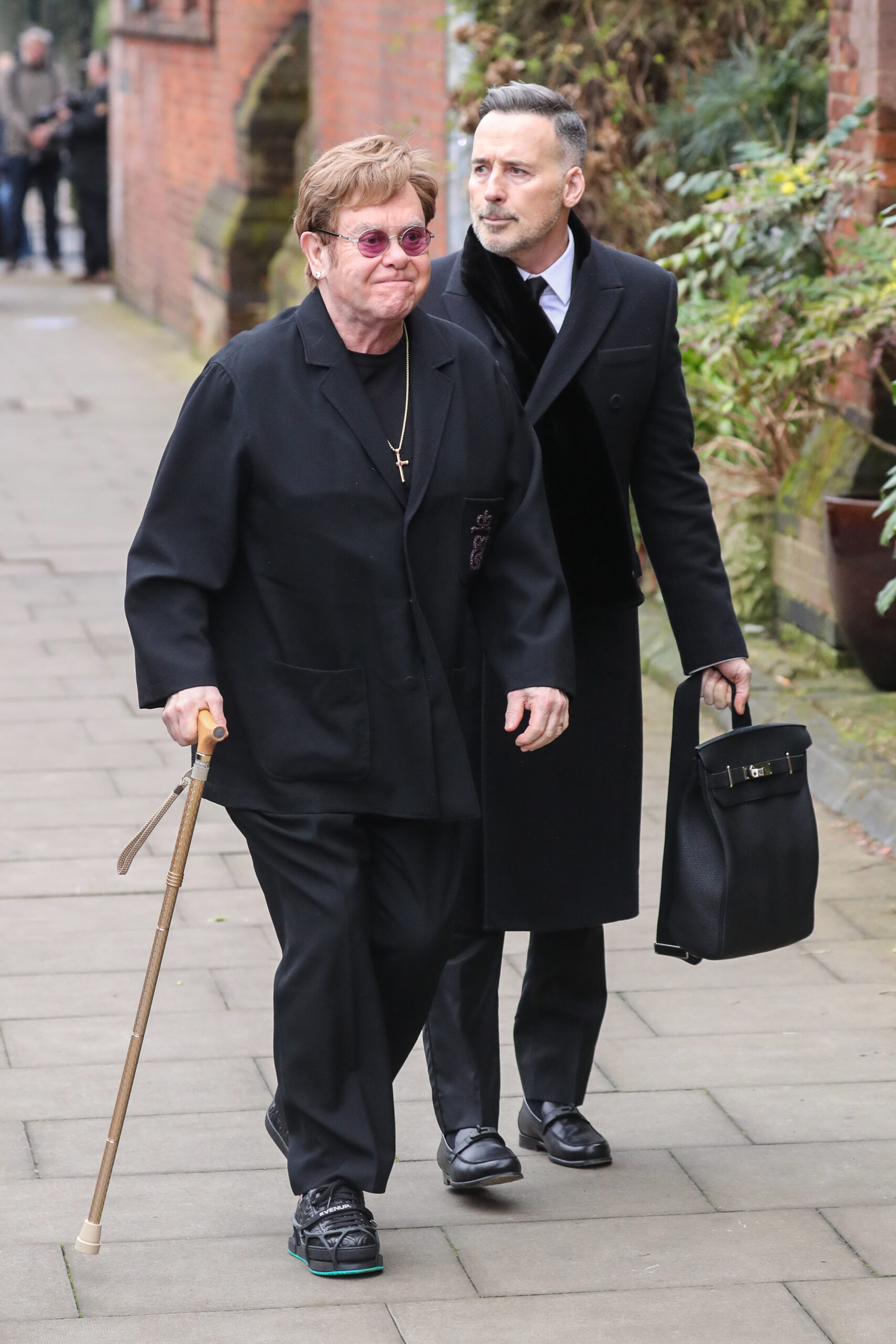 Elton John uses cane to walk alongside his husband David Furnish