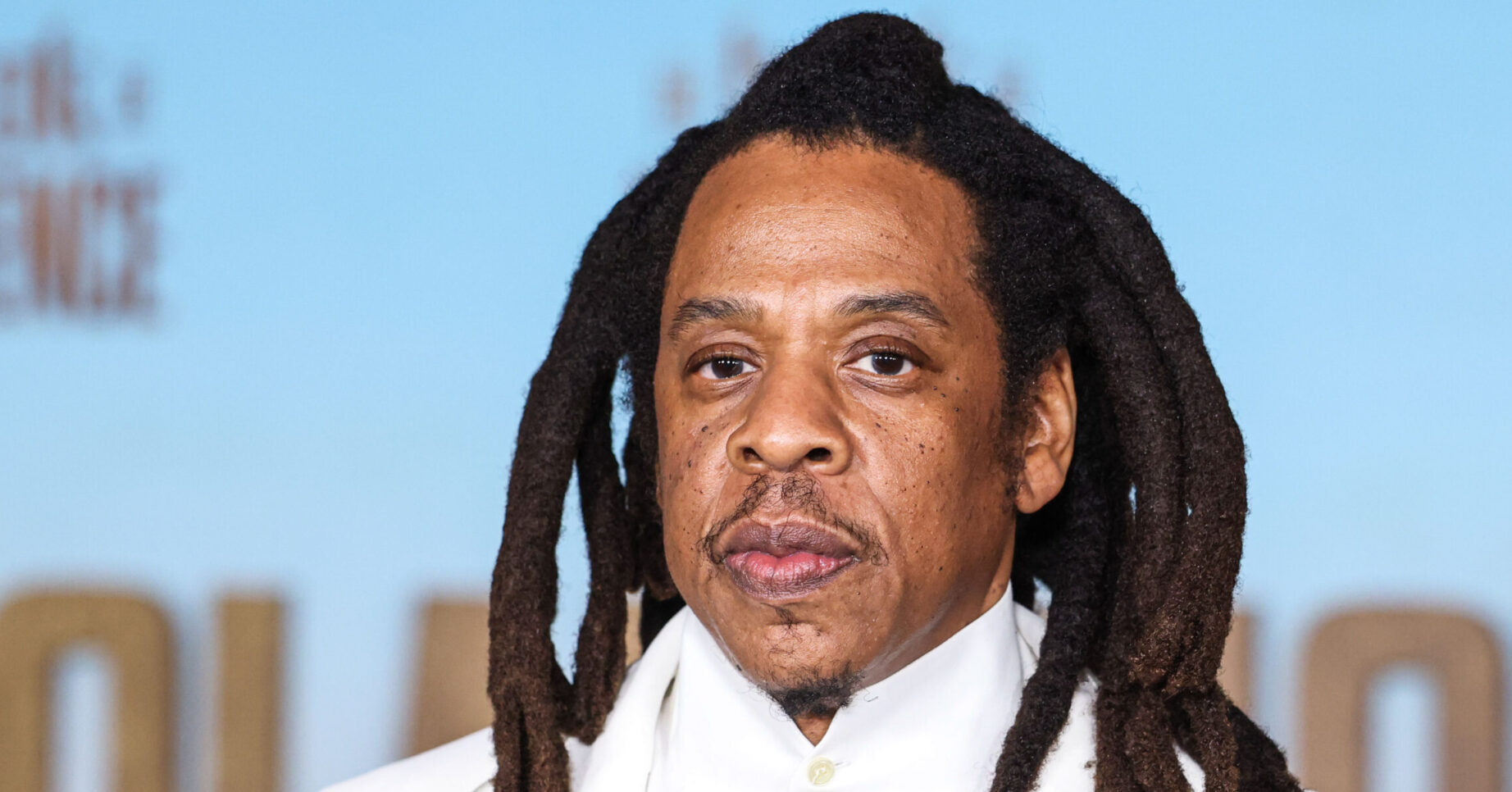 Jay-Z with long hair, wearing a white suit, at a premiere in New York