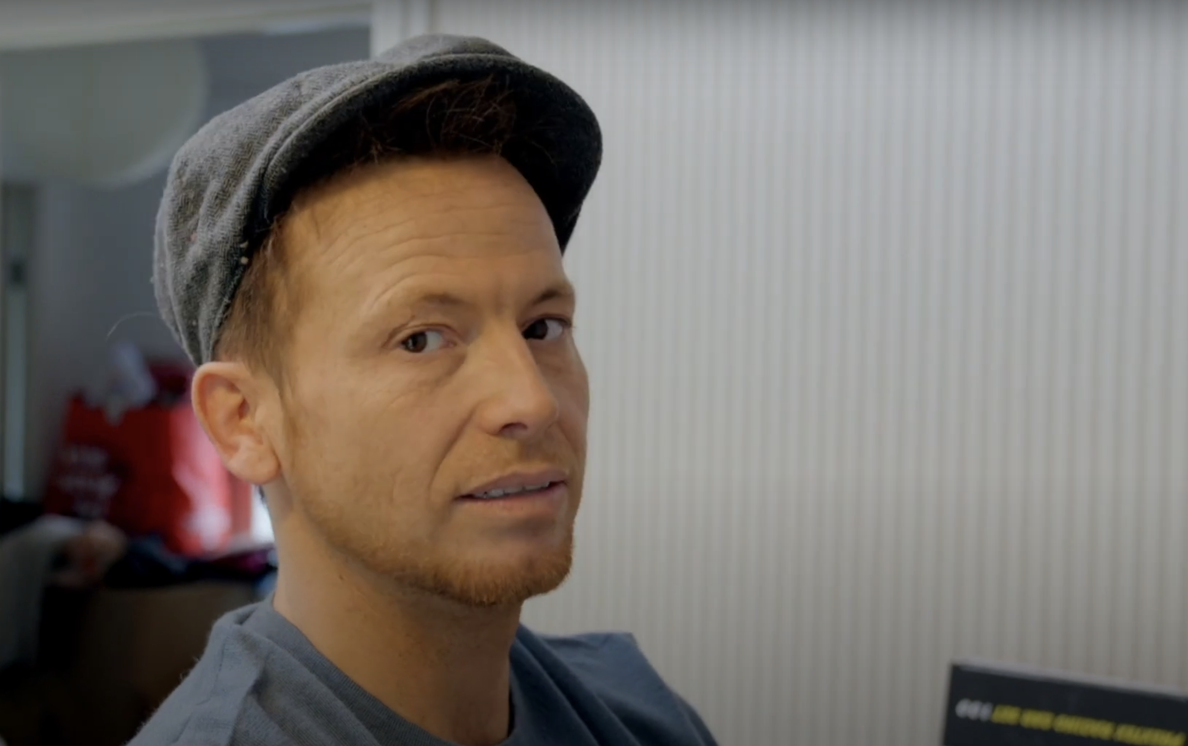 Close up shot of Joe Swash in a flat cap