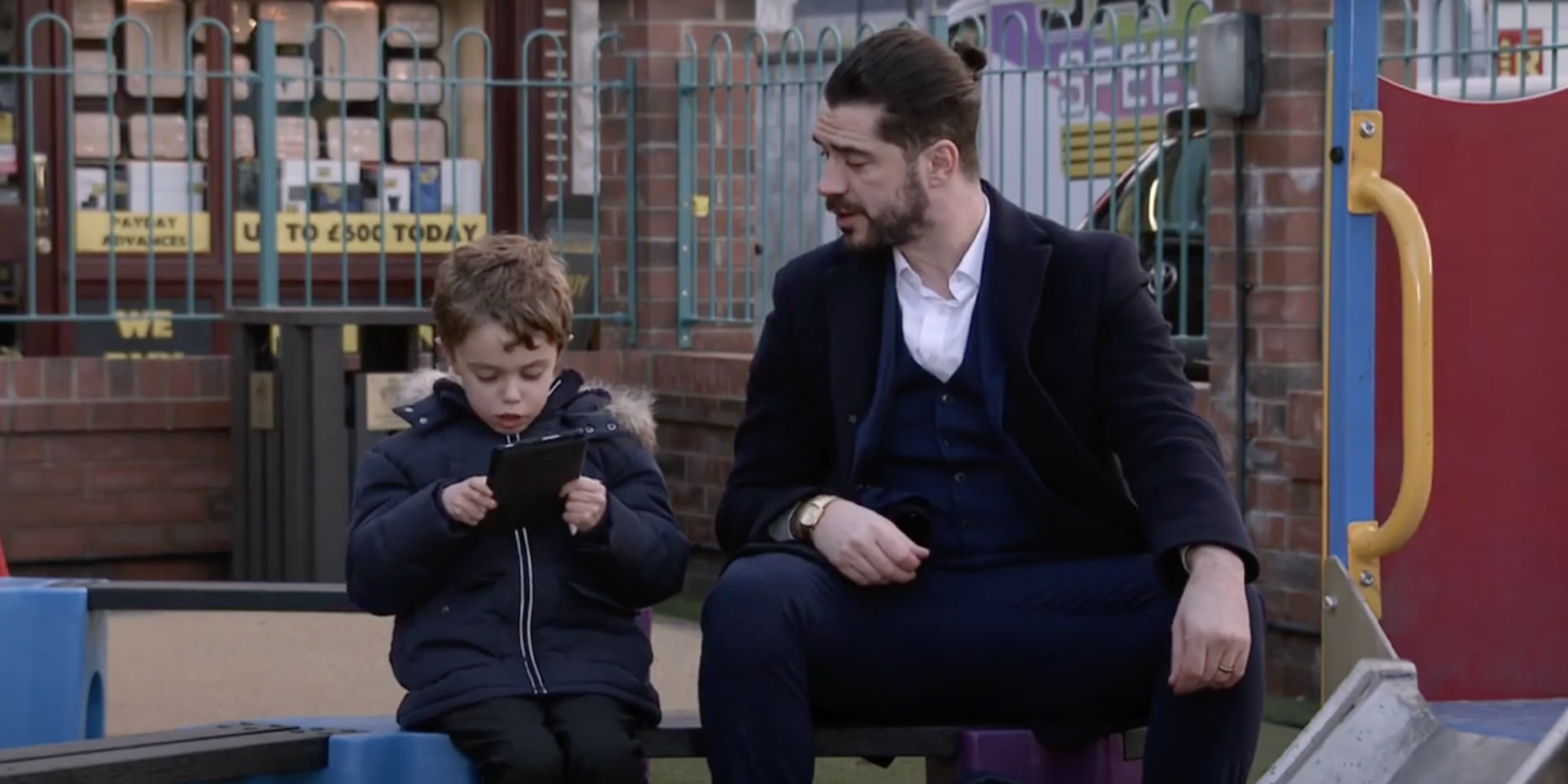 Corrie: Harry and Adam sit on a bench
