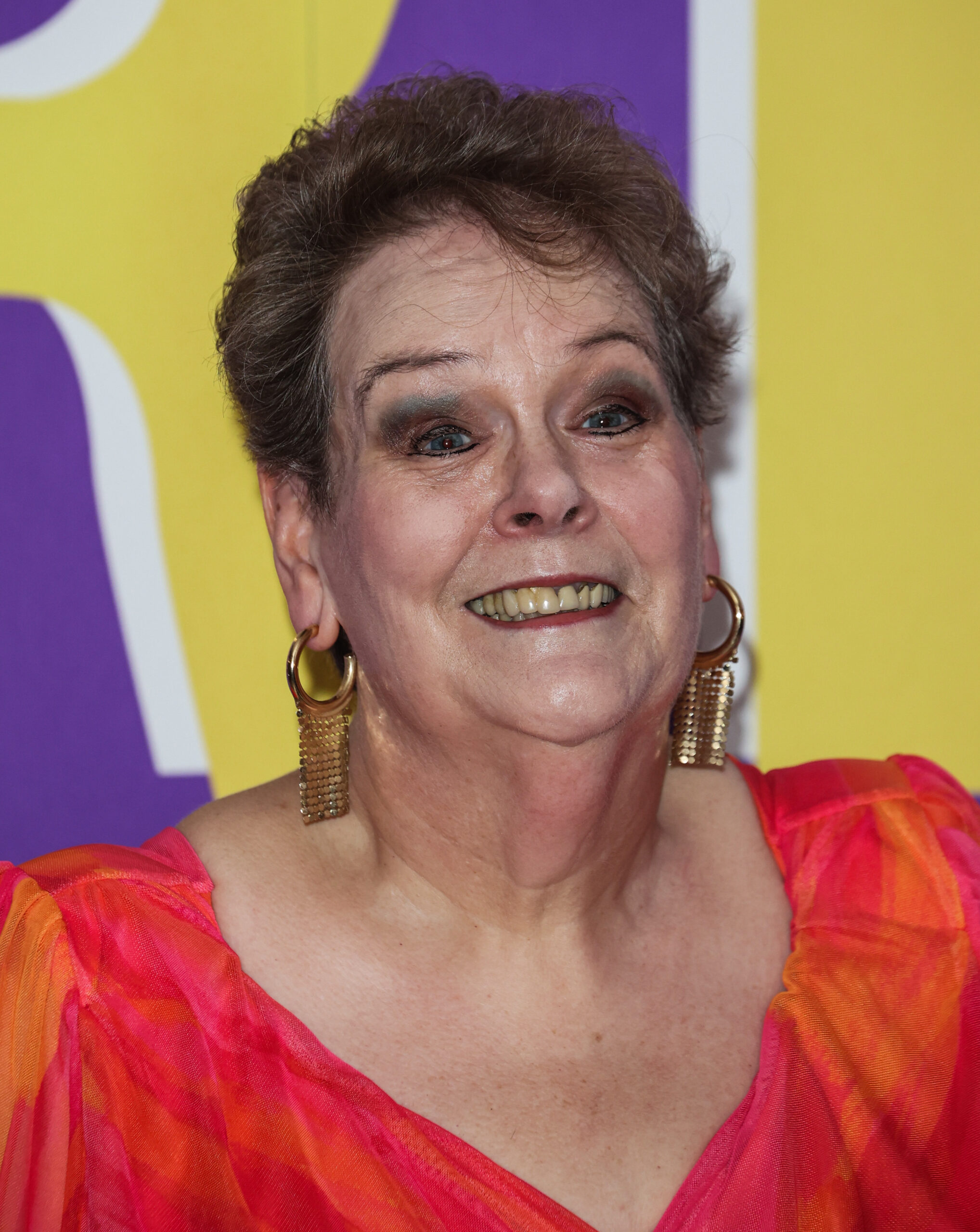 Anne Hegerty poses on red carpet in a crimson dress