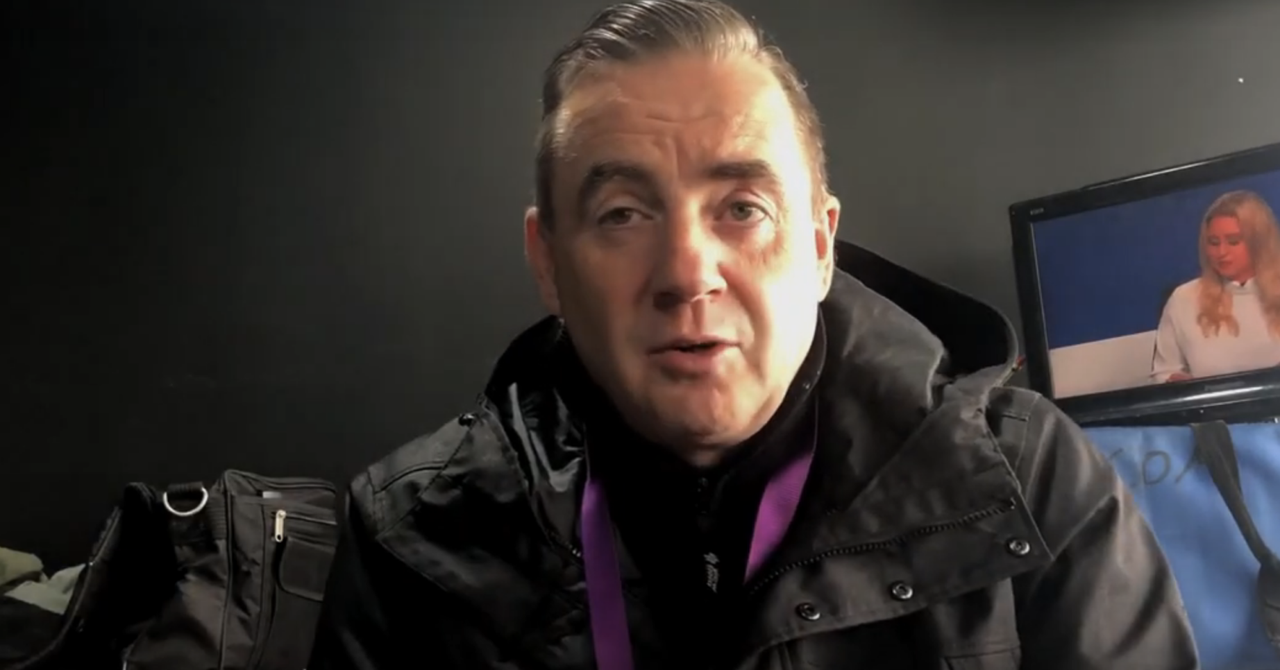 John Hunt in a black raincoat with the sun shining on one half of his face