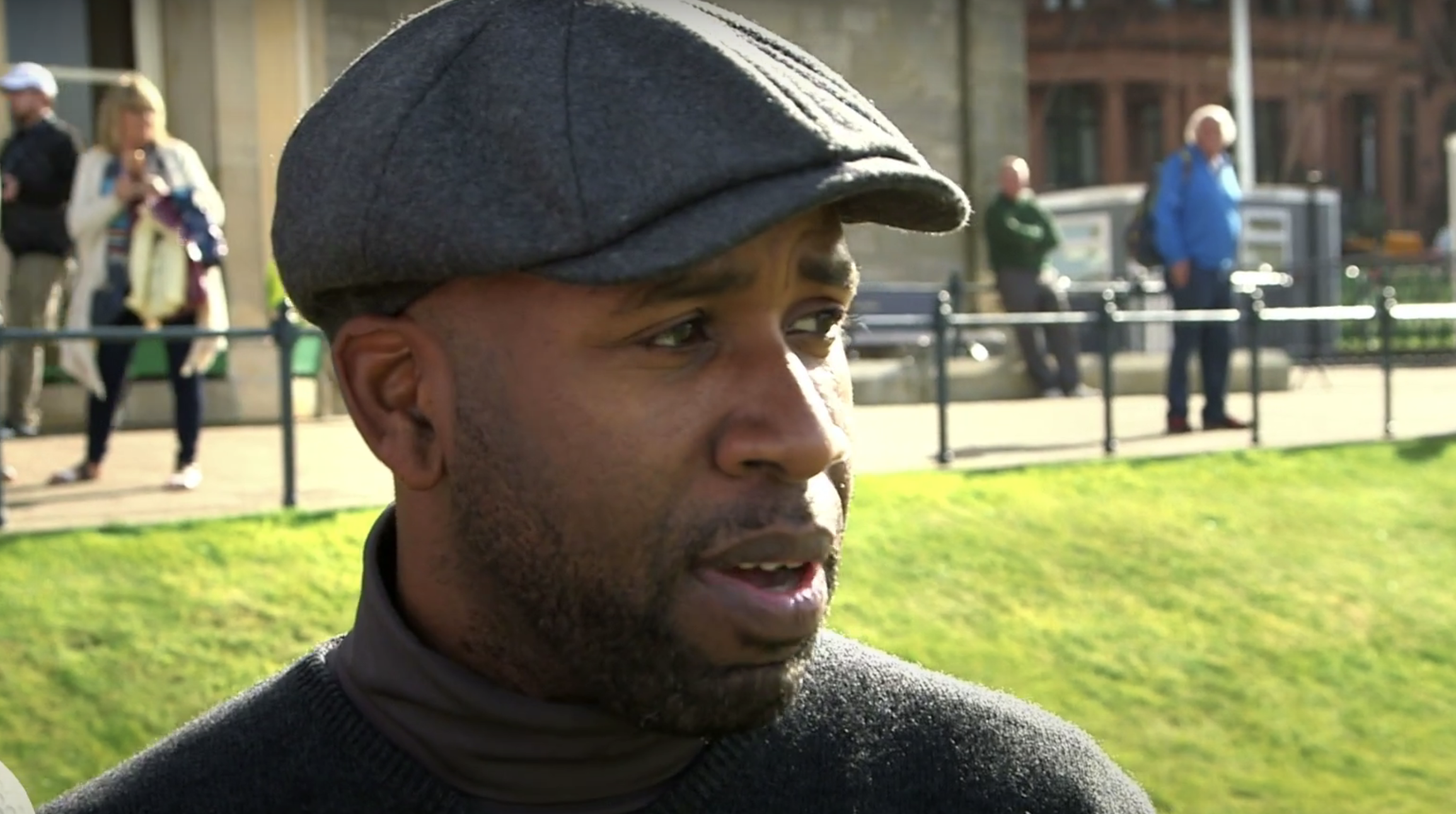 DJ Spoony aka Johnathan Joseph in a flatcap being interviewed outdoors