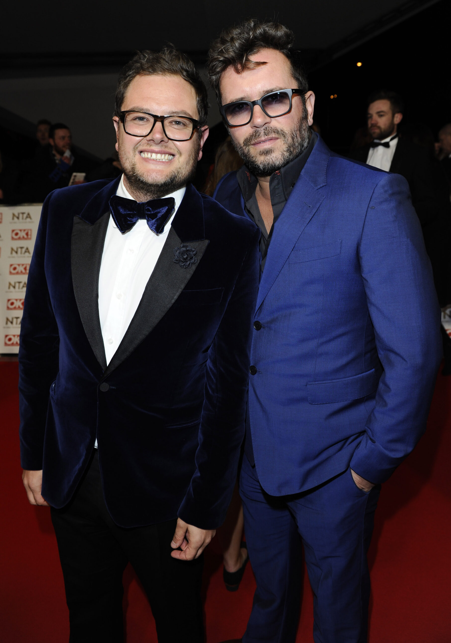 Alan Carr smiling and his ex husband wearing sunglasses