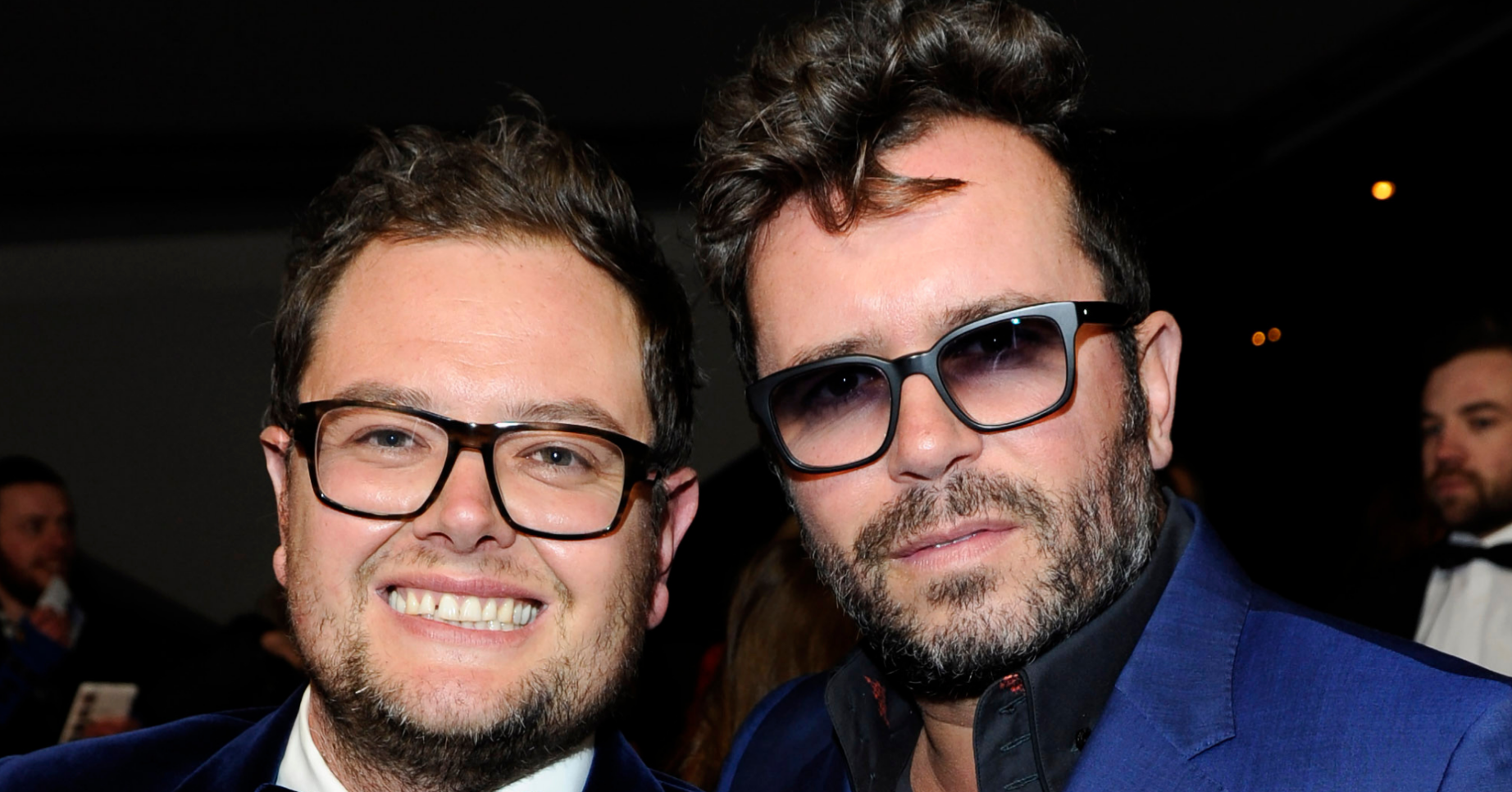 Alan Carr smiling and his ex husband wearing sunglasses