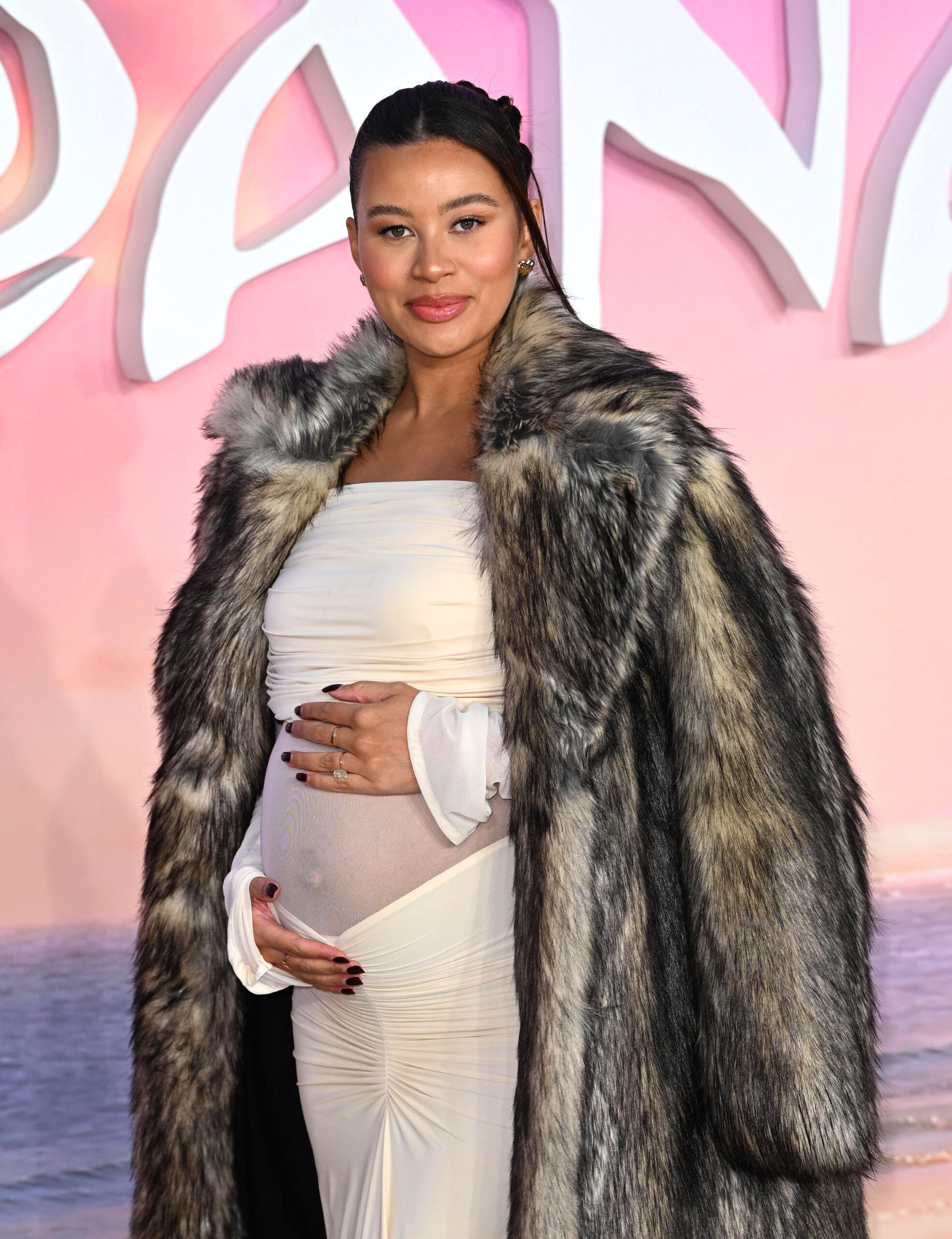 Montana Brown cradling her baby bump posing on red carpet 