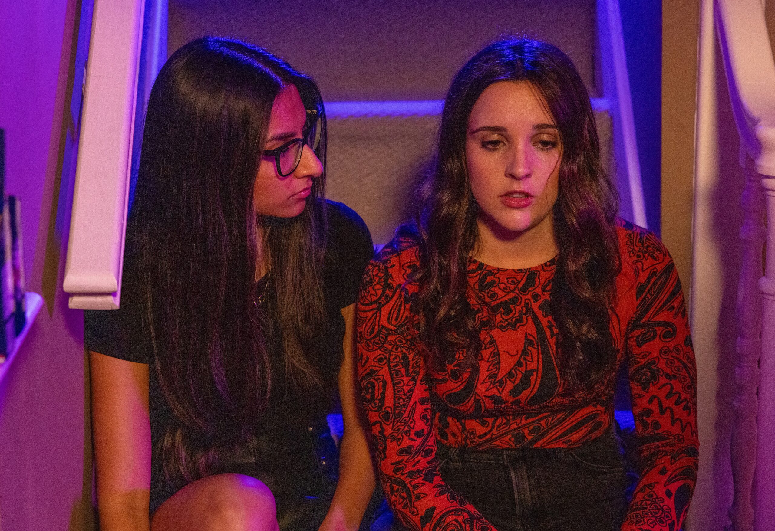 Amy looks upset as she sits on the stairs with Asha on Corrie