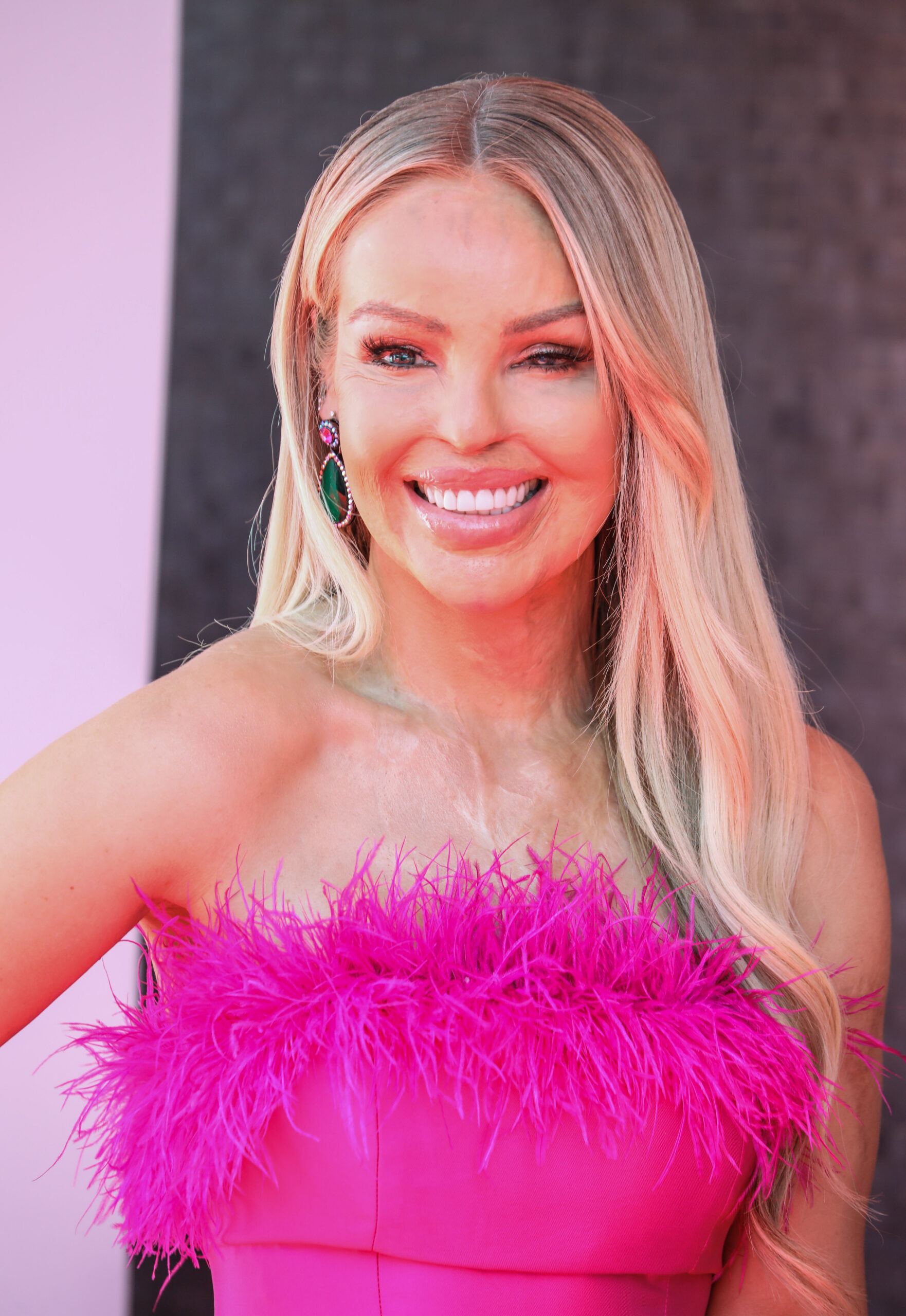 Katie Piper smiling in a pink feathered dress
