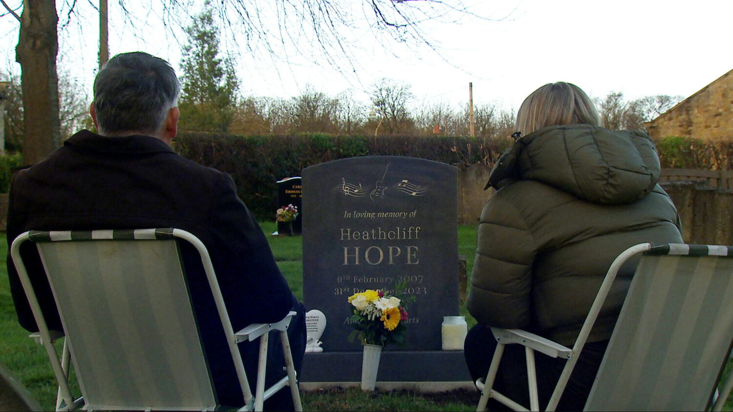 Cathy and Bob sitting by Heath headstone in Emmerdale