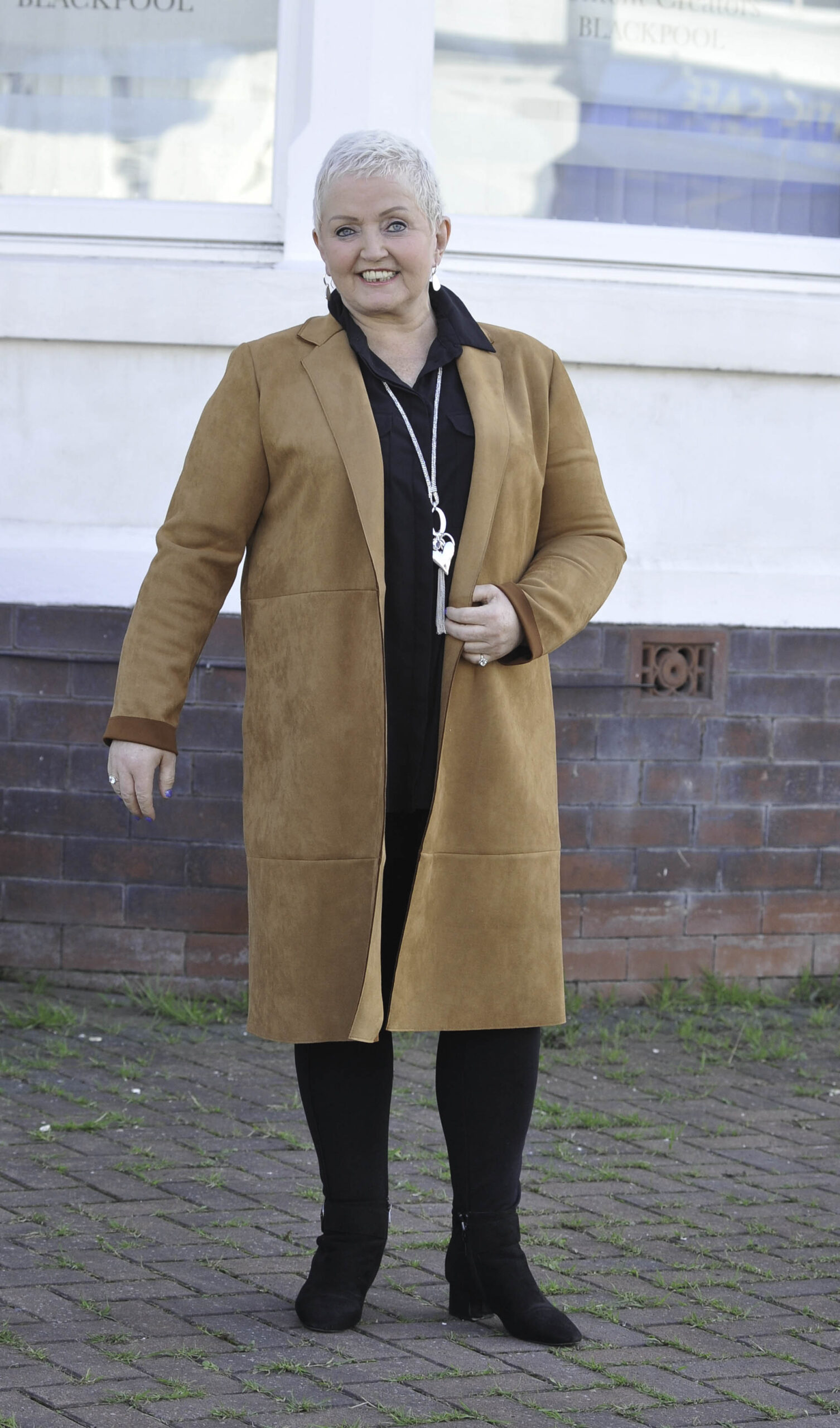 Linda Nolan smiling in a big brown coat