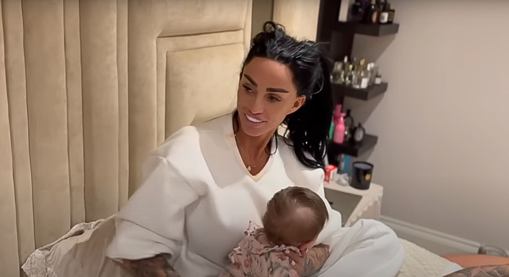 Katie Price looking to her right while holding a baby 