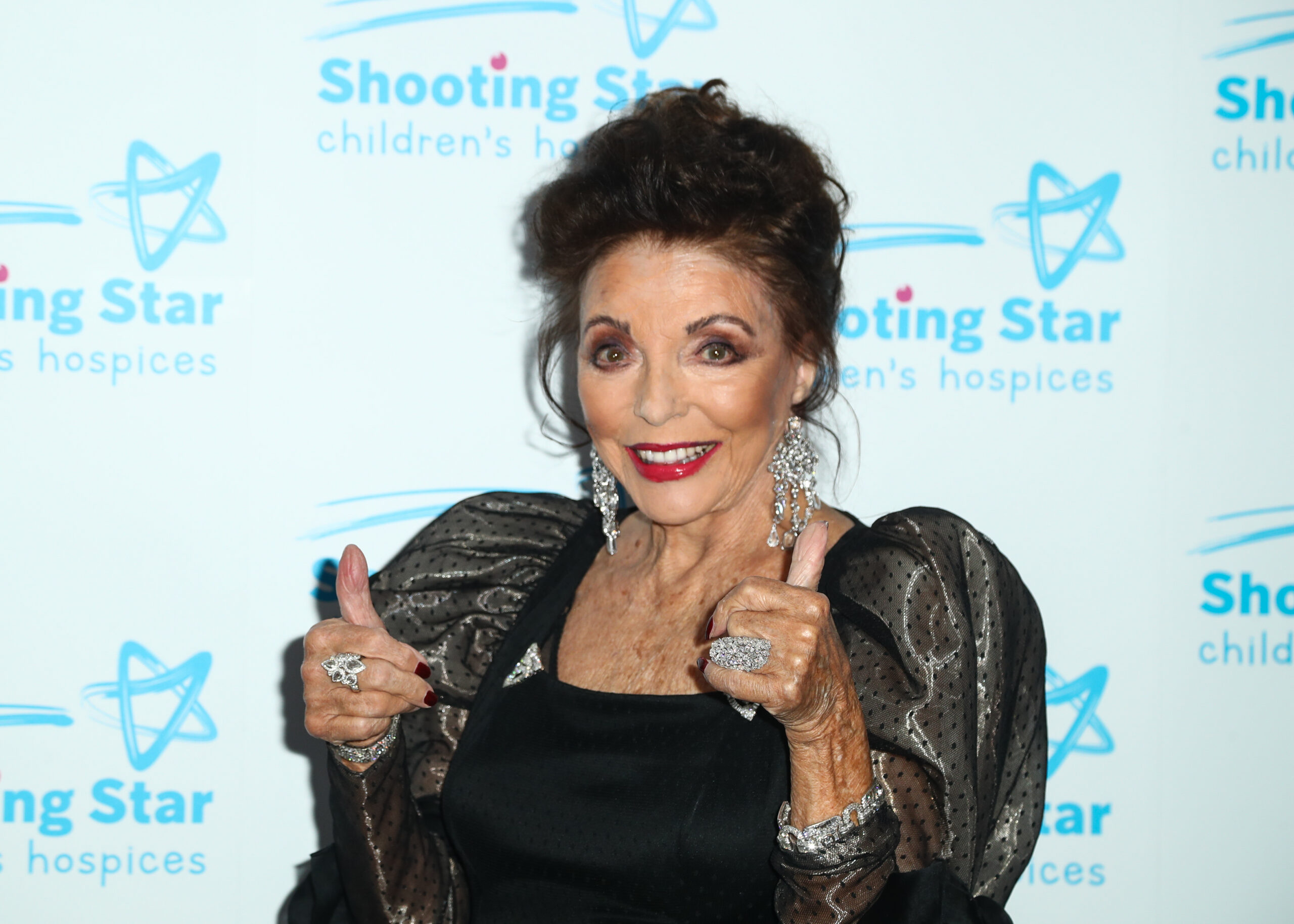 Joan Collins giving the thumbs up on the red carpet
