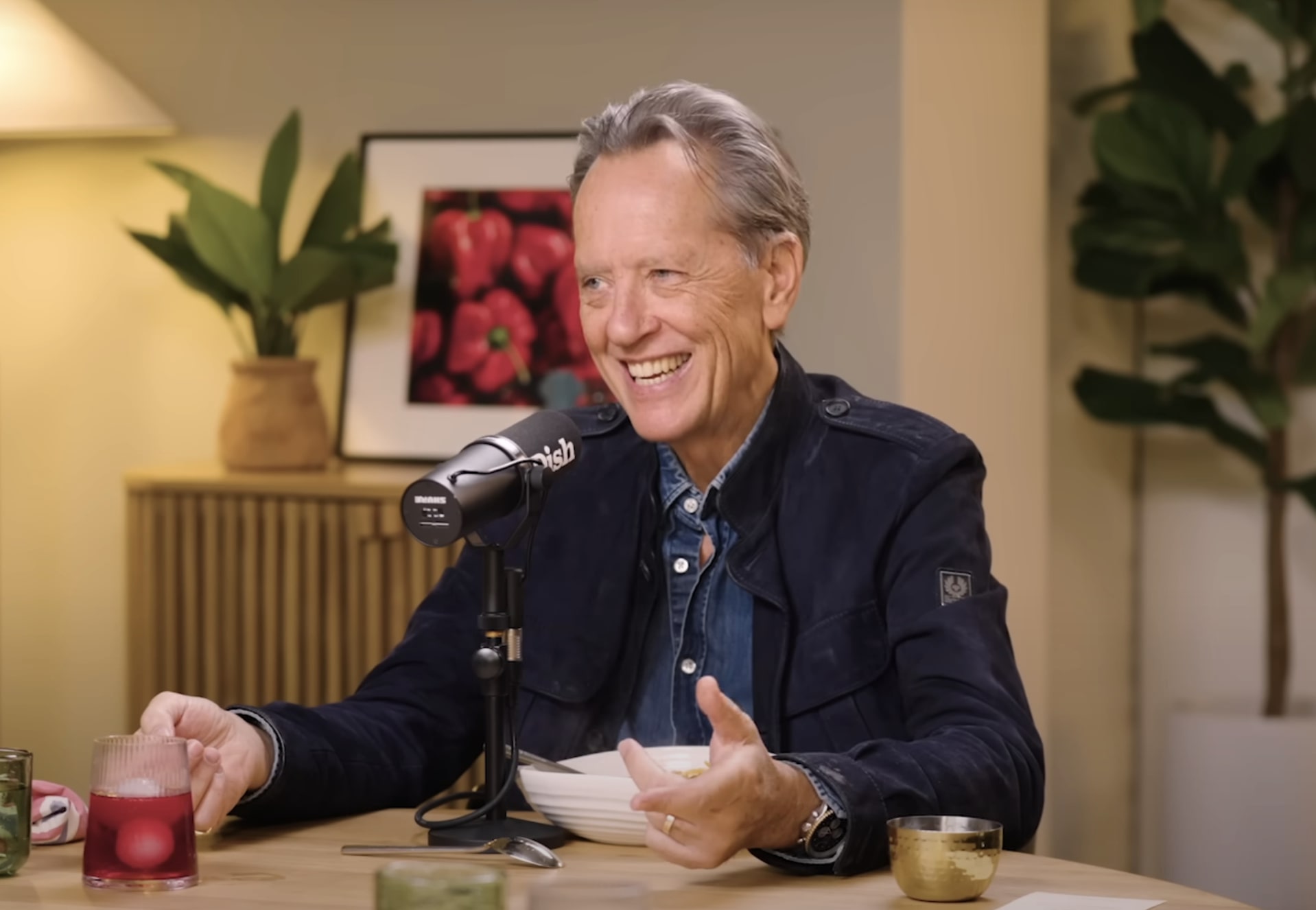 Richard E Grant smiling and gesturing during a recording of the Dish podcast