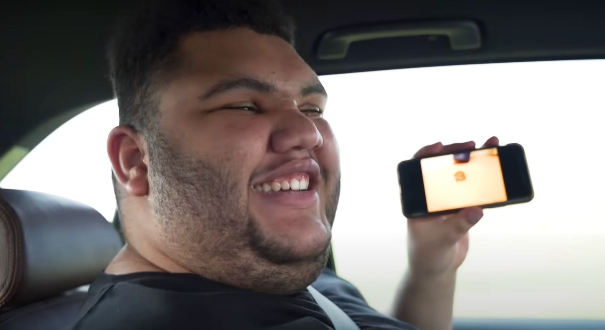 Harvey Price holding a phone and smiling