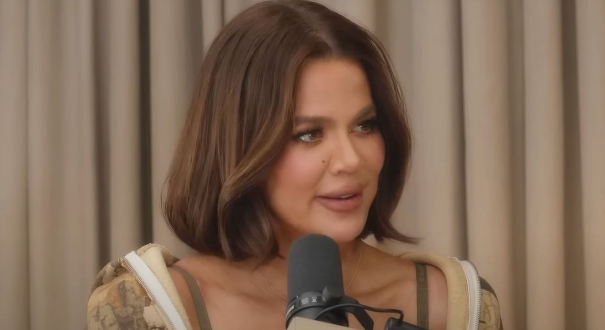 Khloe Kardashian talking into a mic on her podcast