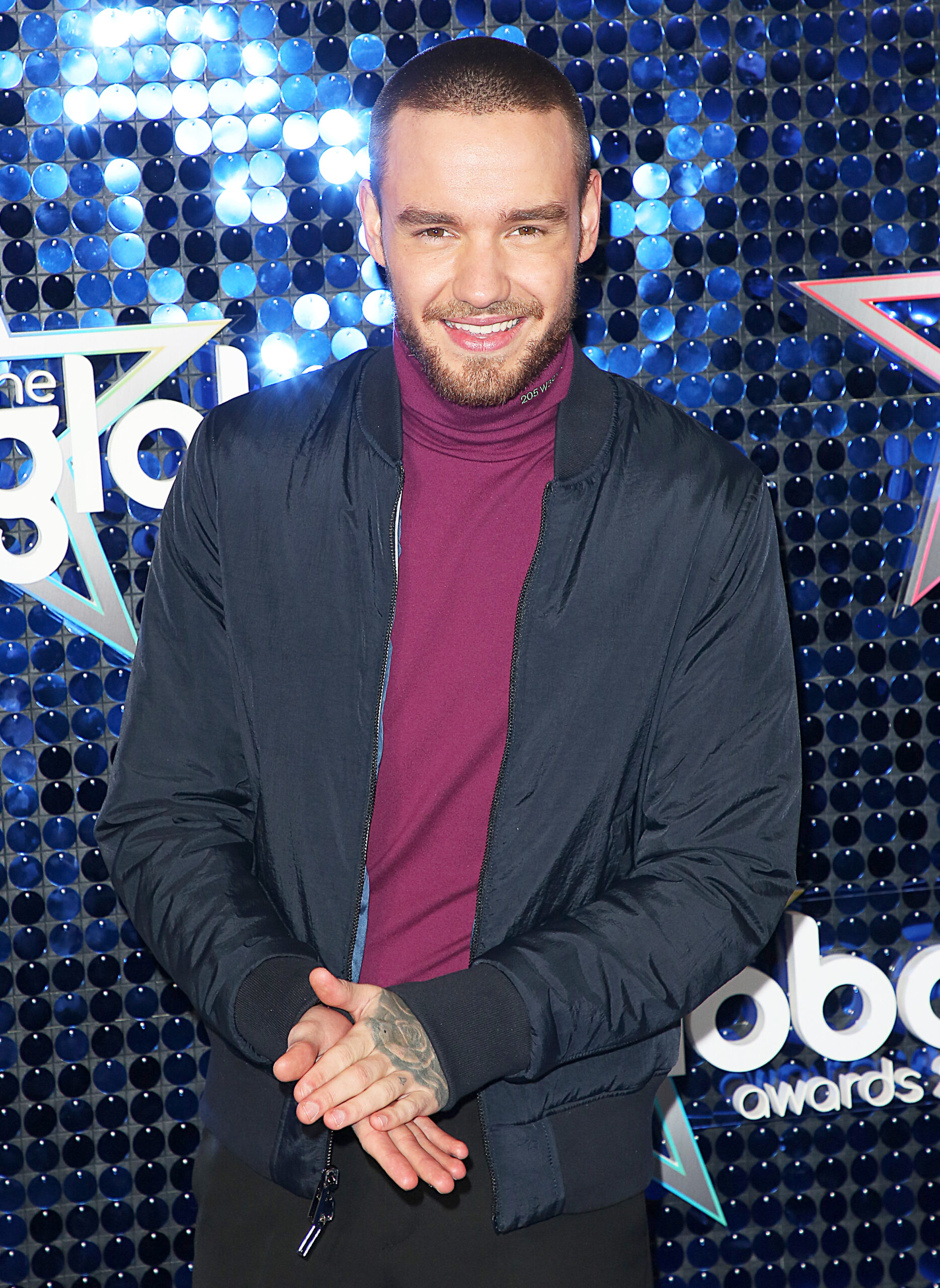 Liam Payne smiling against a blue glitter backdrop
