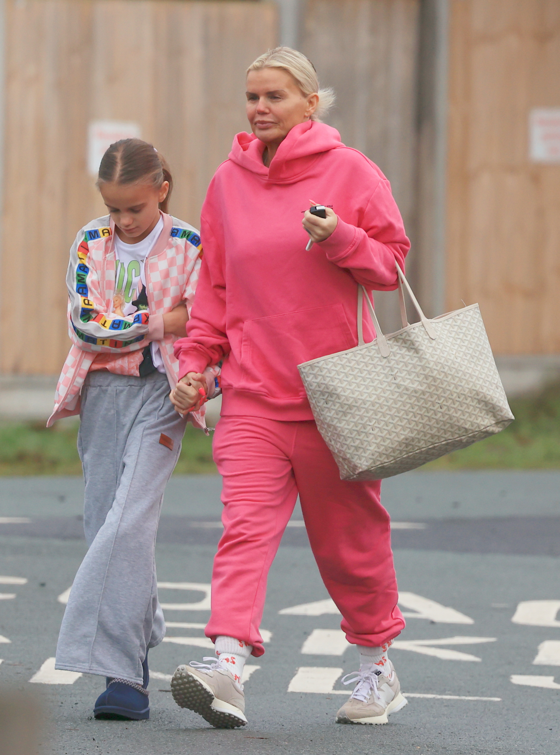 Kerry Katona in a pink tracksuit holding her daughter's hand