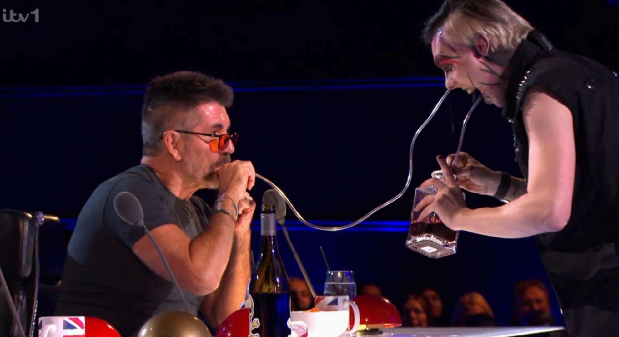 Simon Cowell drinking through a tube from Auzy Blood's nose