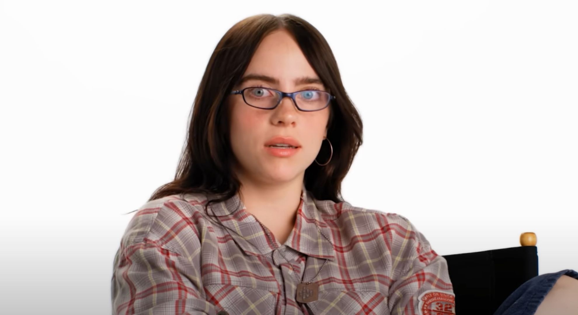 Billie Eilish wears a checkered shirt and glasses