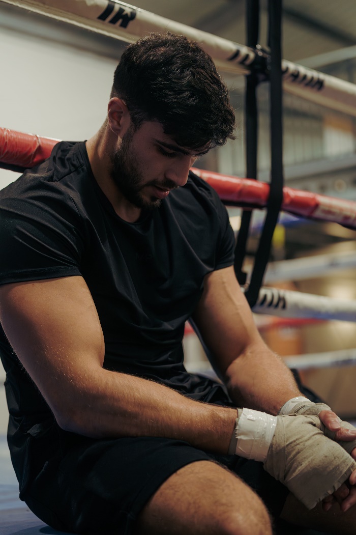 Tommy Fury sat on the edge of a boxing ring looking down