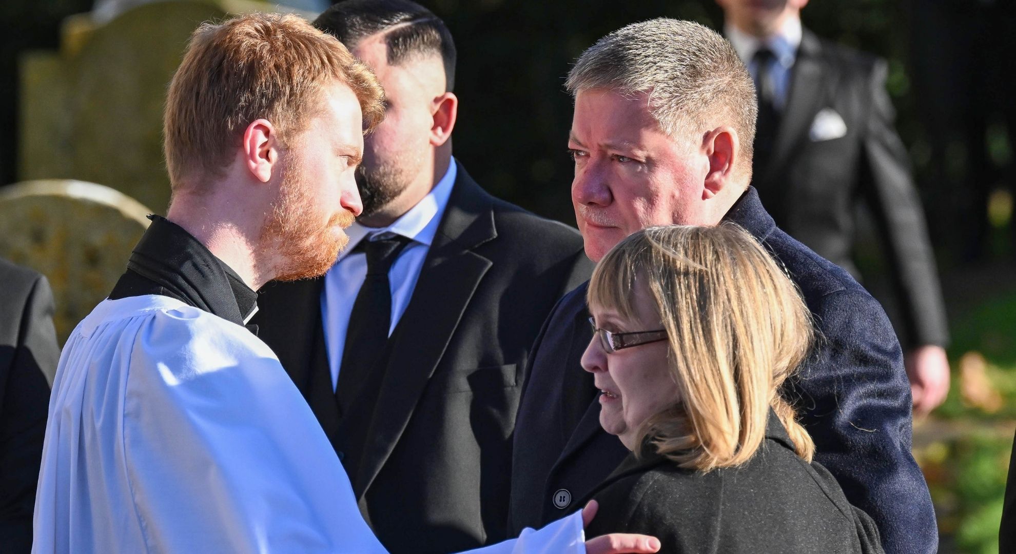Liam Payne's parents grieving at his funeral with a priest dressed in a white robe