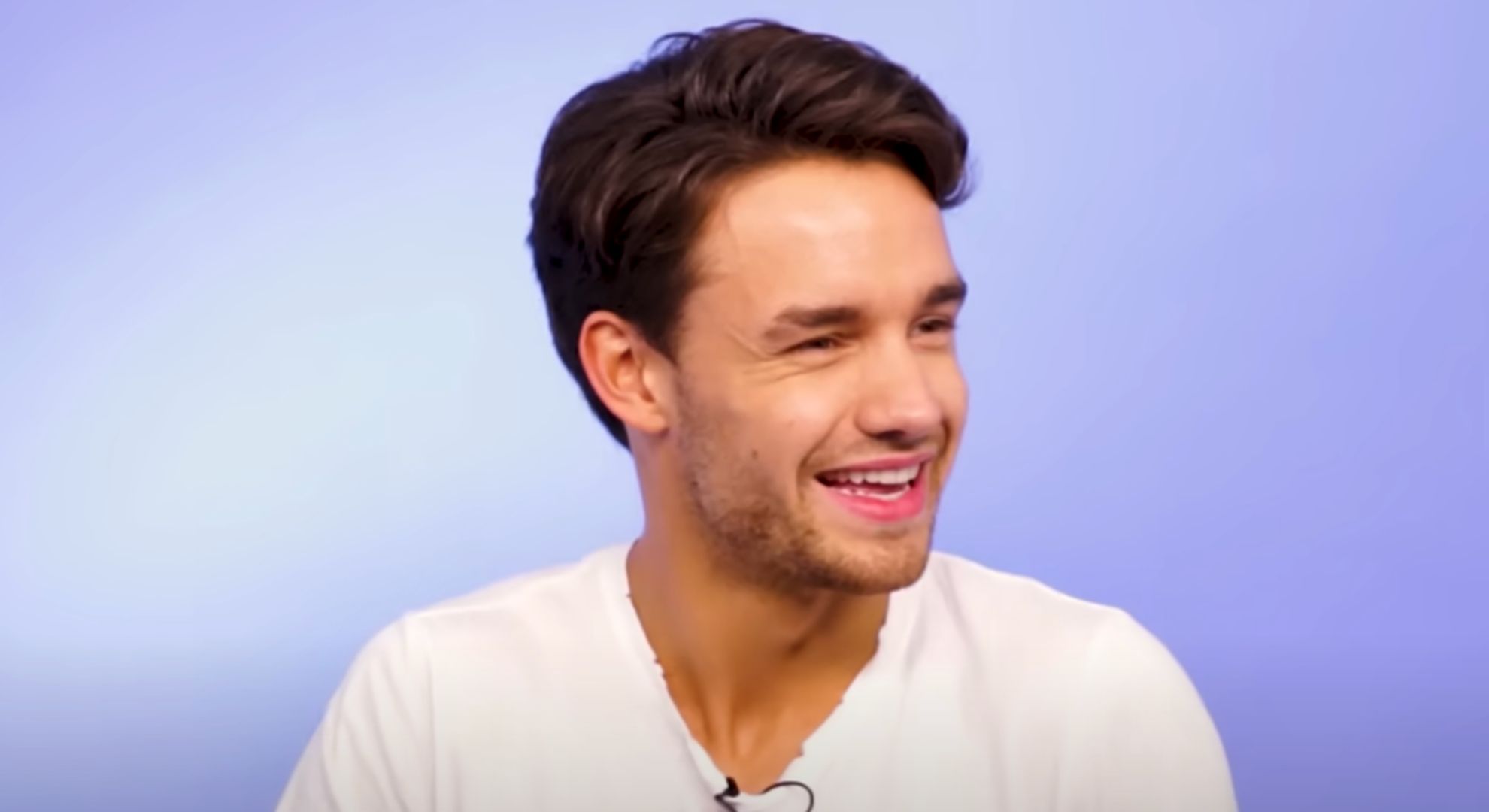 Liam Payne wears a white t-shirt and smiles