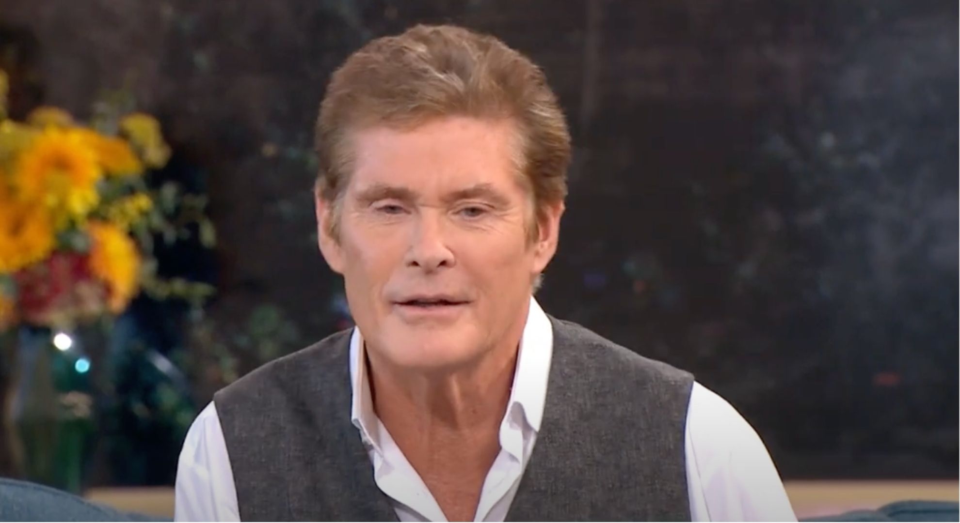David Hasselhoff wears a white shirt and grey vest