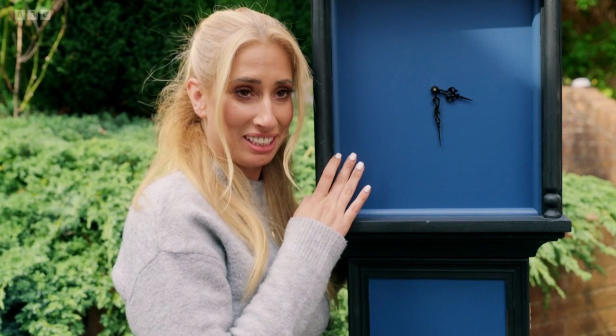 Stacey Solomon smiling next to a clock on Sort Your Life Out