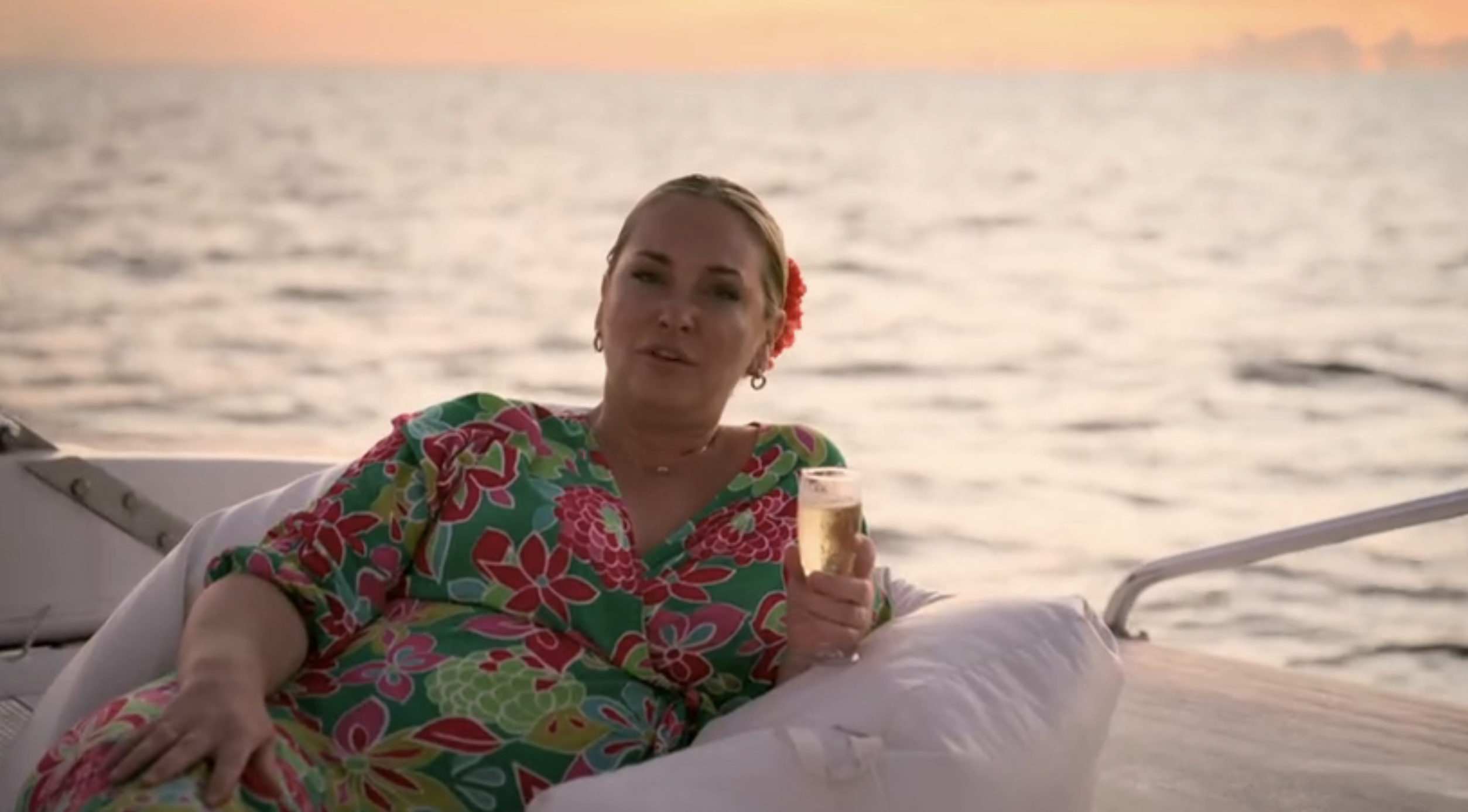 Josie Gibson by the sea with a glass of champagne